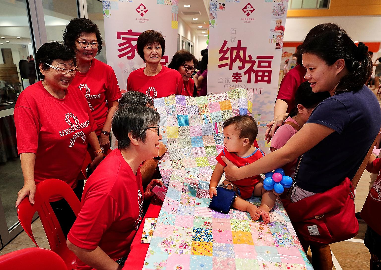 Housewife Amy Loh (right), 35, with her seven-month-old baby, Ajay Tan, at the booth of the Granny Quilt Project at Radin Mas Community Club yesterday. The Chinese Development Assistance Council (CDAC) piloted the Granny Quilt Project in August last 