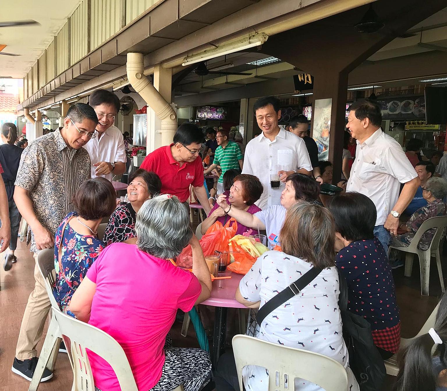 (Standing, from far left) Senior Minister of State Maliki Osman, Ang Mo Kio GRC MP Gan Thiam Poh, Finance Minister Heng Swee Keat and Education Minister Ong Ye Kung talking to residents at Hougang Village, which is part of Sengkang South division, du