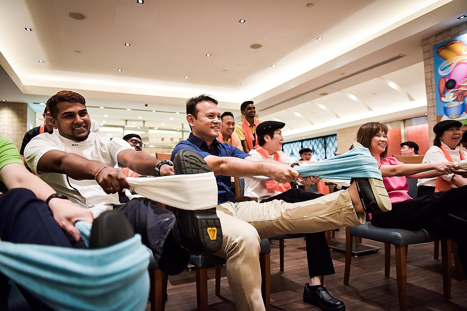 Minister of State for Manpower and National Development Zaqy Mohamad (in blue) and Senior Minister of State for Health Amy Khor (in pink), who co-chair a committee on workplace safety and health, participating in a stretching exercise with workers fr