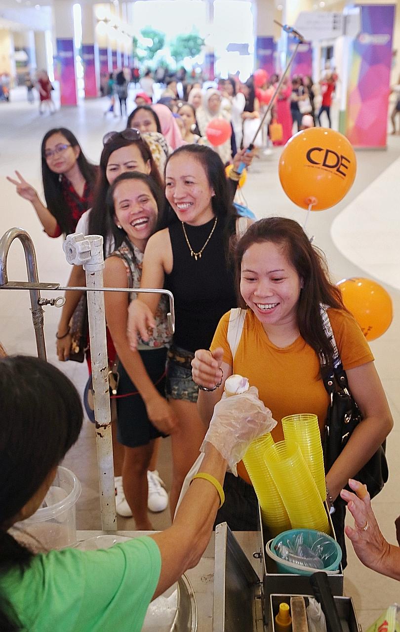 Maids queueing for free ice cream at an event at Heartbeat@ Bedok organised by the Centre for Domestic Employees yesterday. The Manpower Ministry said the practice of employers safekeeping the money of maids poses inconveniences and risks to both par