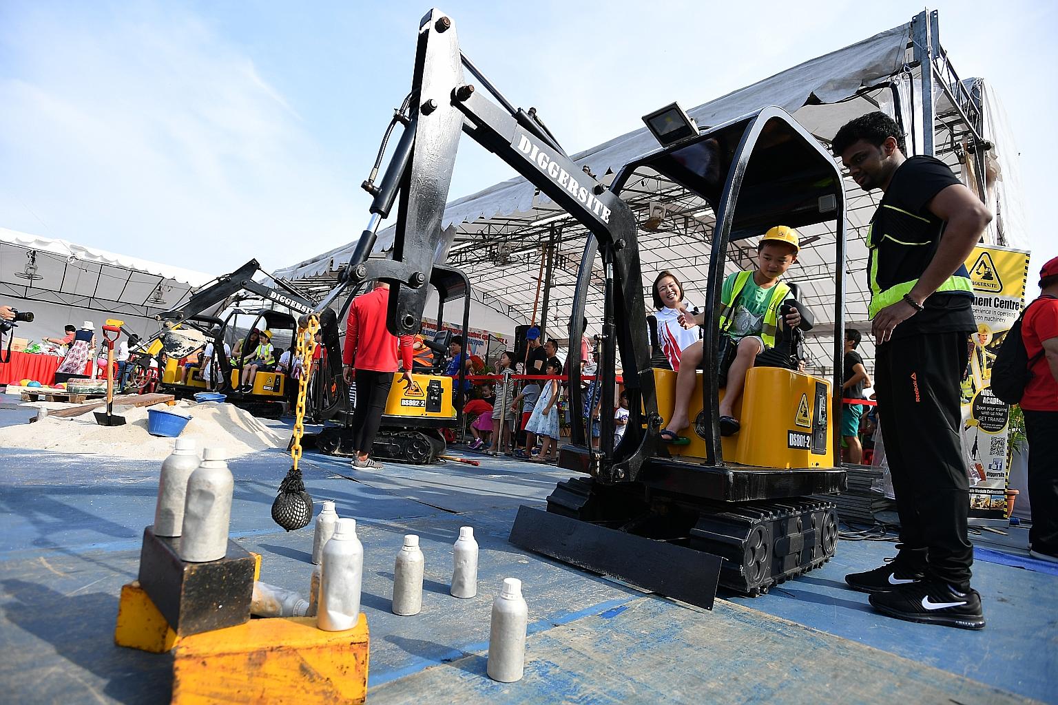 Seven-year-old Zaccheus Ker trying out a wrecking ball machine yesterday at Punggol Town Square, where the Punggol Town Hub ground-breaking ceremony and Children's Day carnival were held. The hub, which will be located opposite Waterway Point shoppin