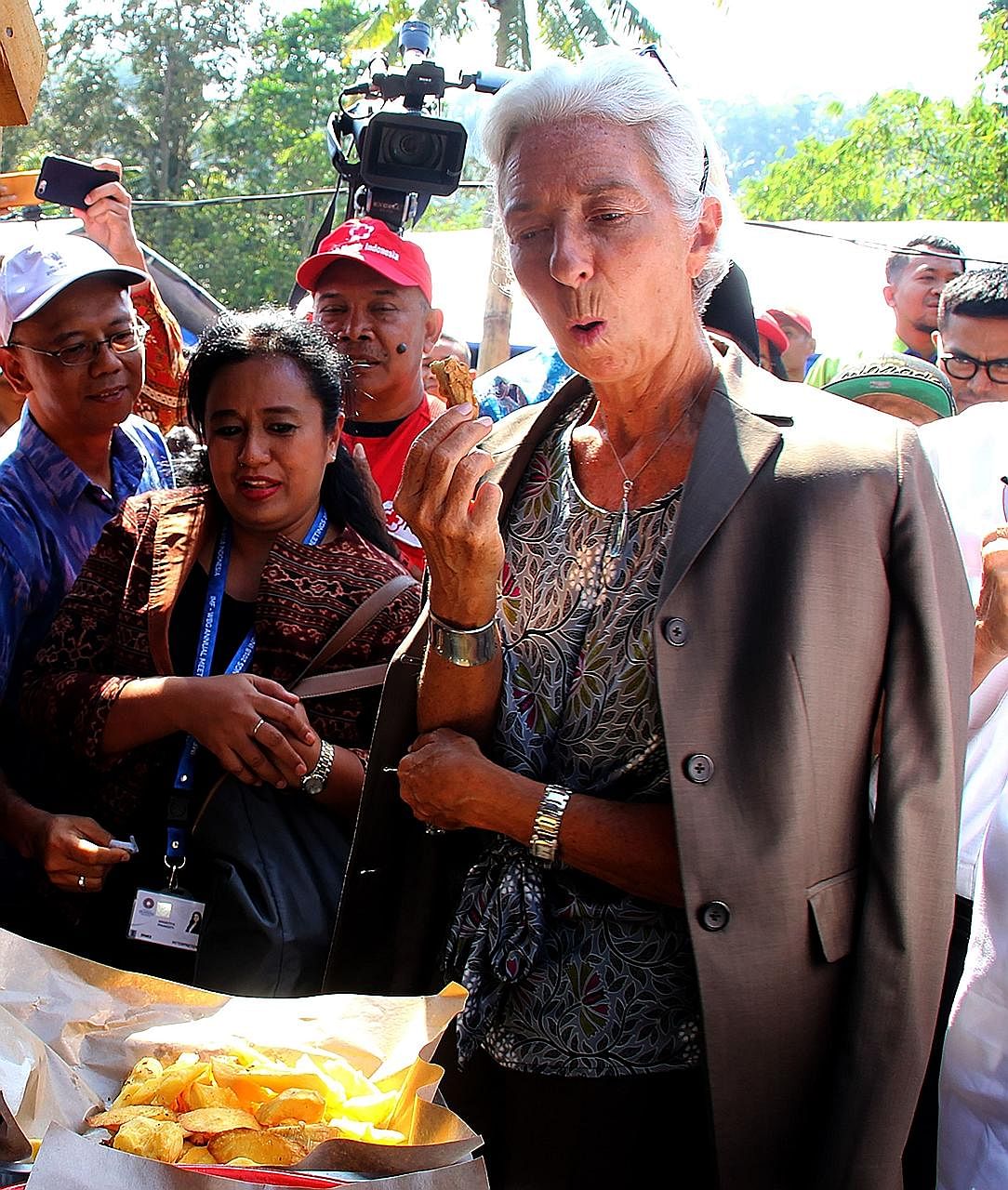 IMF chief Christine Lagarde sampling fried banana on a visit to Gunung Sari on Lombok Island on Monday. Supporters of presidential hopeful Prabowo Subianto have said the government was insensitive in going ahead with the meetings in the aftermath of 