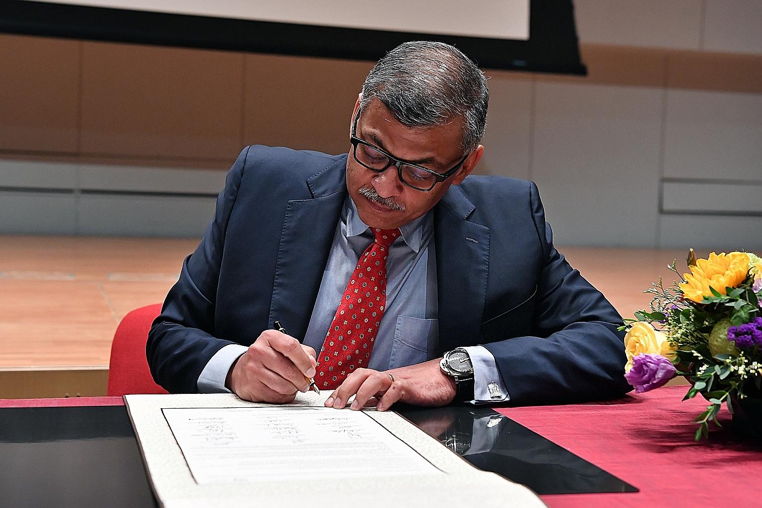 Chief Justice Sundaresh Menon signing the pledge as a witness at the Supreme Court yesterday.