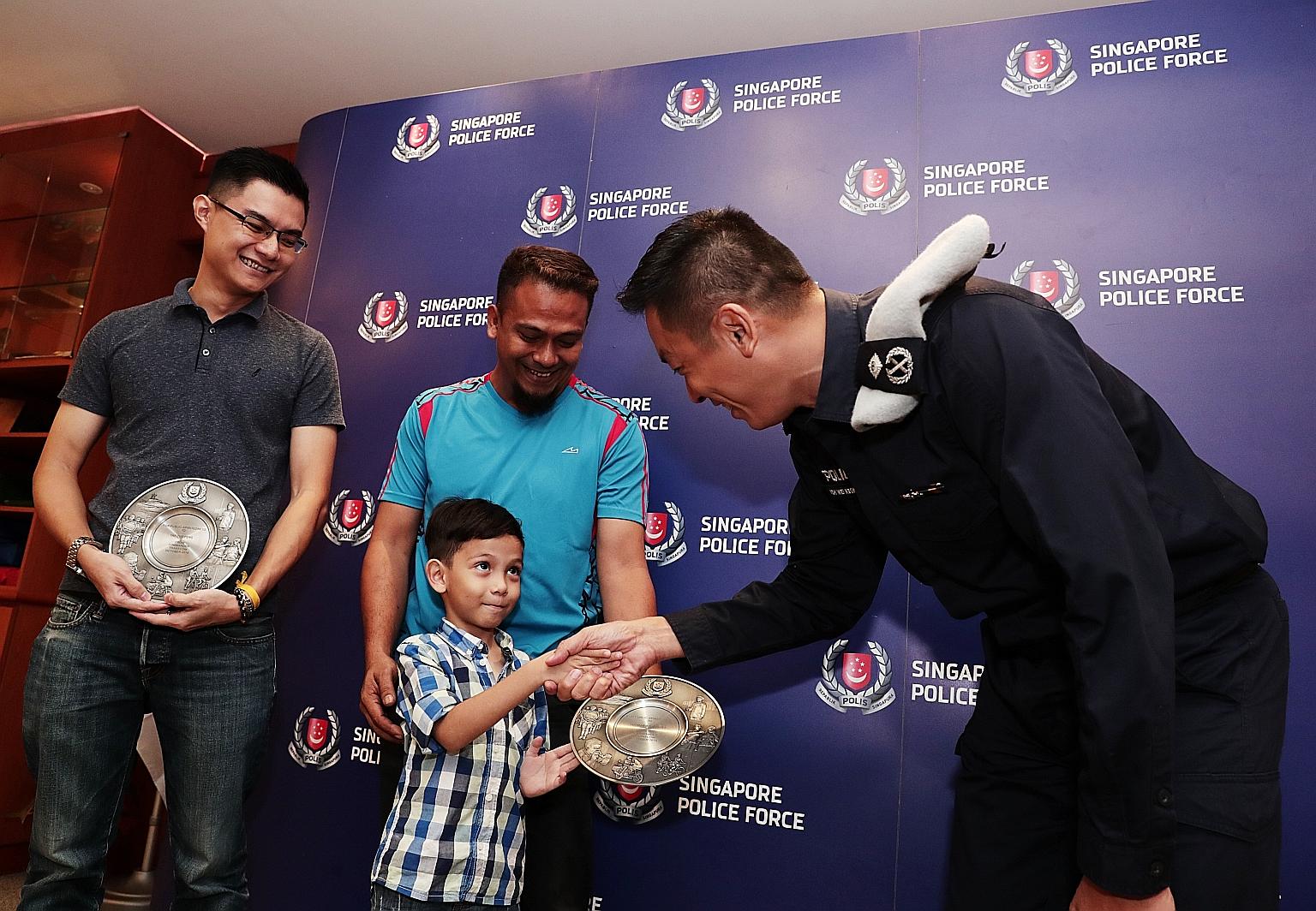 Five-year-old Mohd Ashqil, with his father Yusman Yusoff behind him, greeting Public Transport Security Command Commander Koh Wei Keong at the award ceremony yesterday. Mr Yusman and Mr Yap Zuo Peng (left) both received the Public Spiritedness Award 