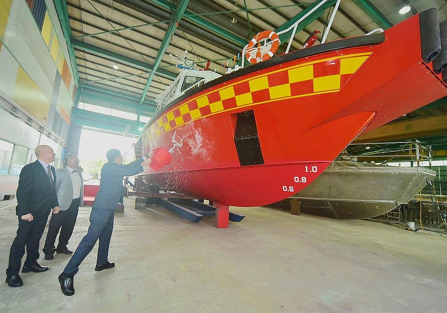 SCDF Commissioner Eric Yap launching the White Swordfish on Wednesday by splashing a bucket of sea water onto the bow. To be deployed at the upcoming Punggol marine outpost, the new vessel is the SCDF's third purpose-built Rapid Response Fire Vessel.