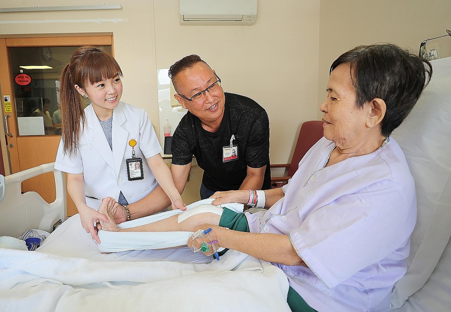 Part-time handyman Lim Thiam Beng and senior physiotherapist Jaclyn Tan giving exercise tips to a knee replacement surgery patient who wanted to be known only as Madam Chong.