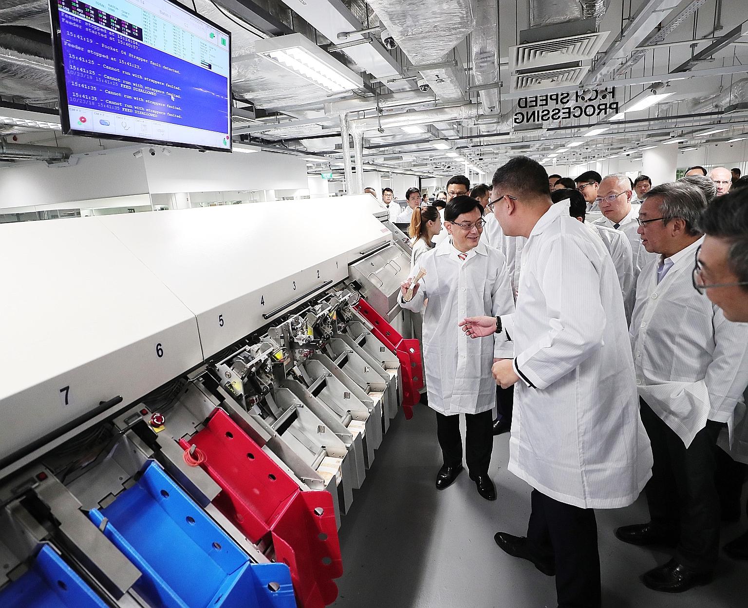 Finance Minister Heng Swee Keat visiting a cash processing centre at the new Certis Commonwealth building yesterday.