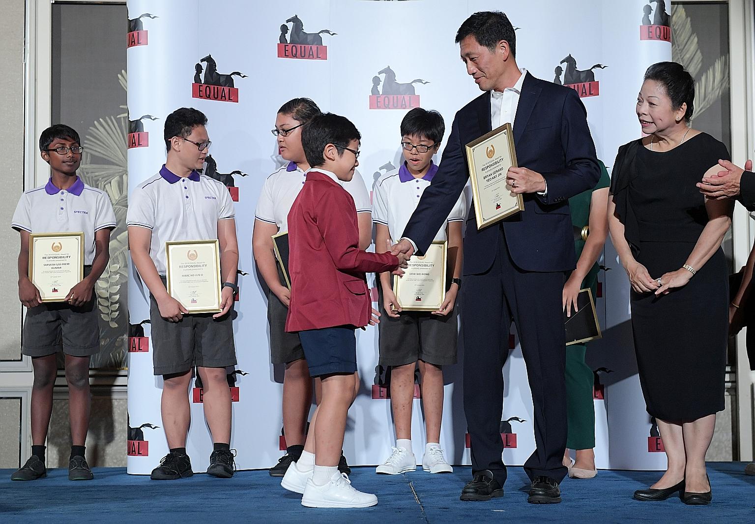 Education Minister Ong Ye Kung presenting Bryan Gerard Yeo with an award at charity group Equal-Ark's gala dinner at the Shangri-La Hotel yesterday. Beside him is Dr Melanie Chew, the founder of Equal-Ark.