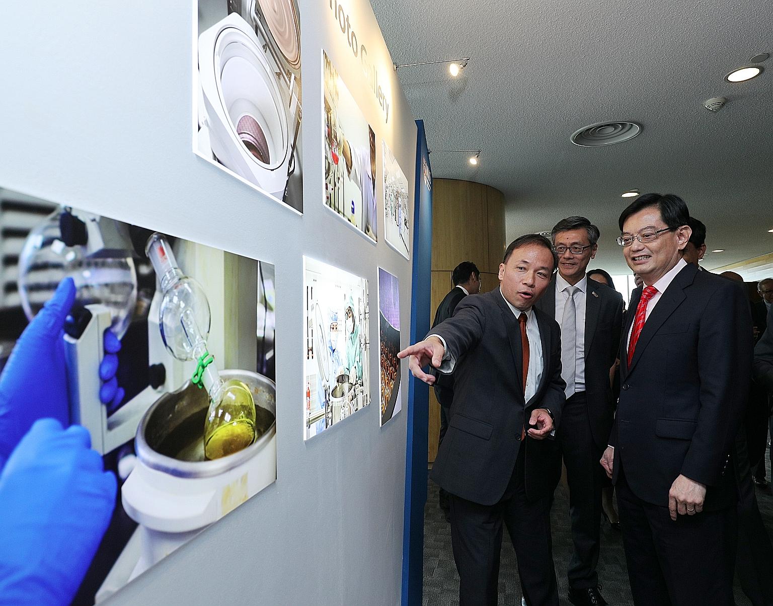 Professor Aaron Thean (left), co-director of the Applied Materials-NUS Advanced Materials Corporate Lab at NUS, showing Finance Minister Heng Swee Keat the exhibits displayed at the launch of the lab yesterday. With them was NUS president Tan Eng Chy