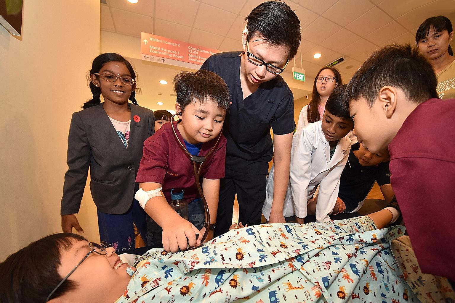 Dr Wong Wen Kai teaching children how to use medical instruments at Alexandra Hospital's open house yesterday.