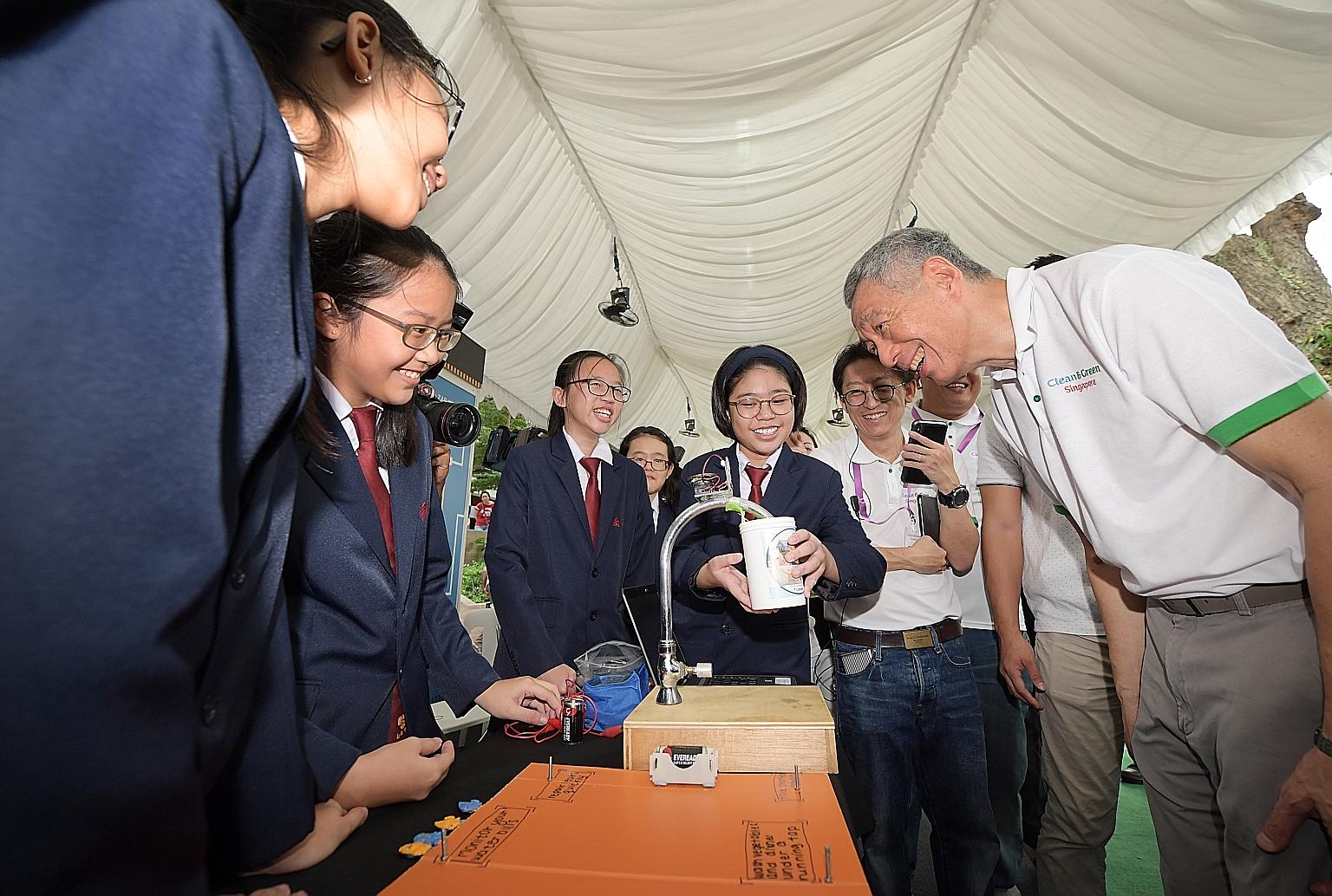 Students from Nan Chiau High School showing Prime Minister Lee Hsien Loong their project, which uses a water sensor installed at the tap to help users save water, at the Clean and Green Singapore carnival at Wisma Geylang Serai yesterday.