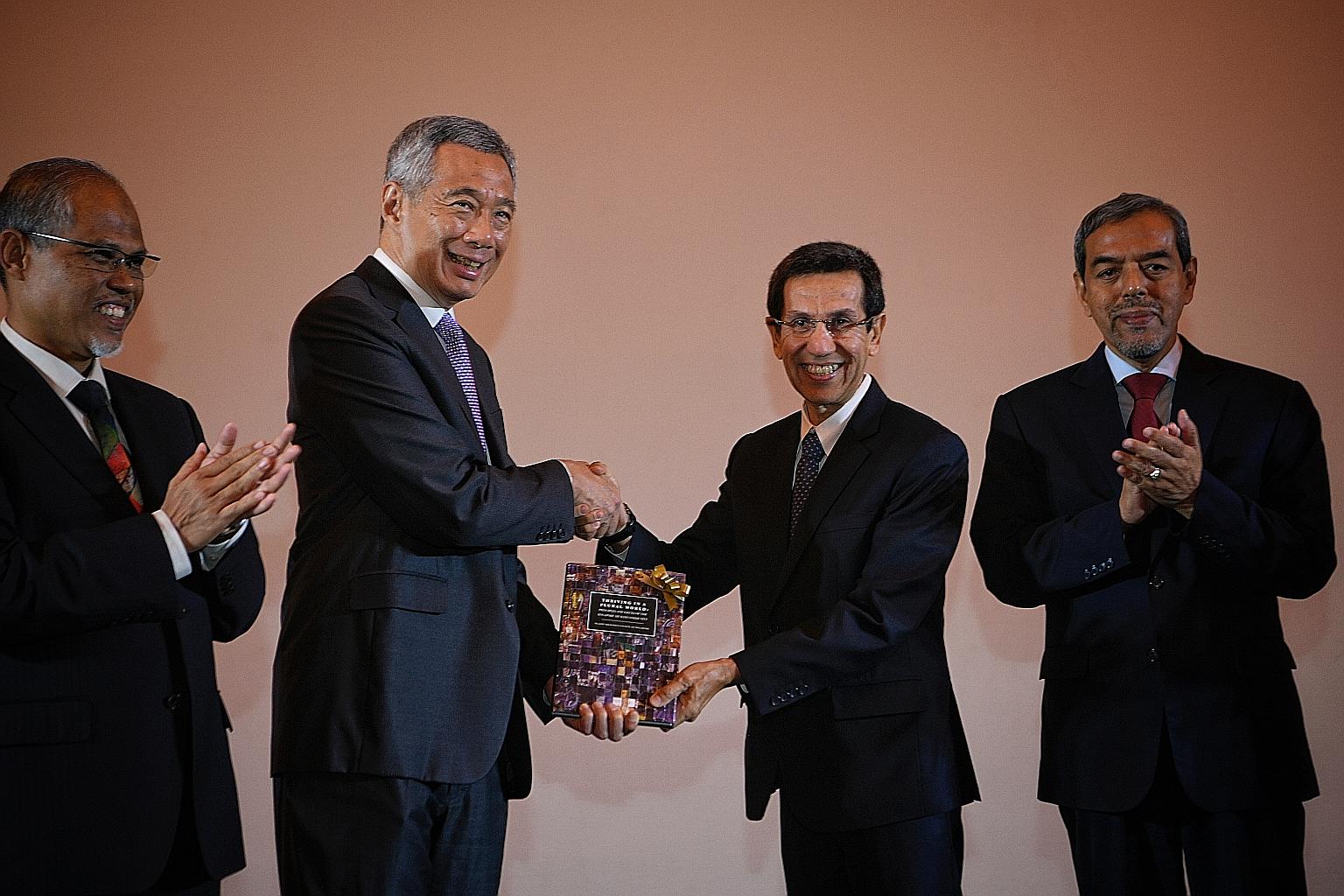 Prime Minister Lee Hsien Loong receiving a copy of the book Thriving In A Plural World: Principles And Values Of The Singapore Muslim Community from Muis president Mohammad Alami Musa at the conference to mark Muis' 50th anniversary yesterday. With t