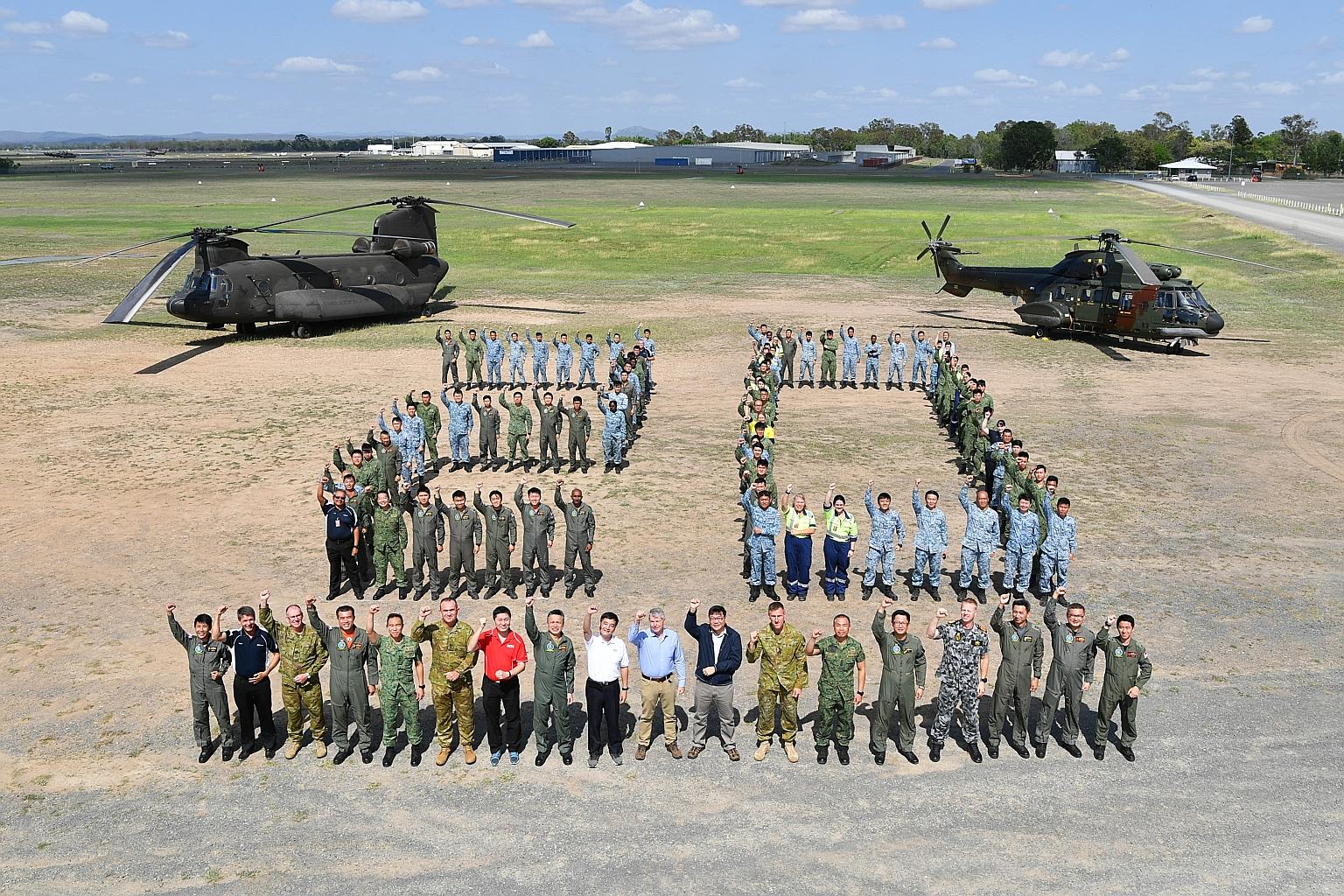 RSAF officers and their Australian defence partners do a "20" formation with a CH-47D Chinook (left) and AS332 Super Puma (right). Among those in the front row are Senior Minister of State for Defence Heng Chee How (white shirt), and Australian Assis