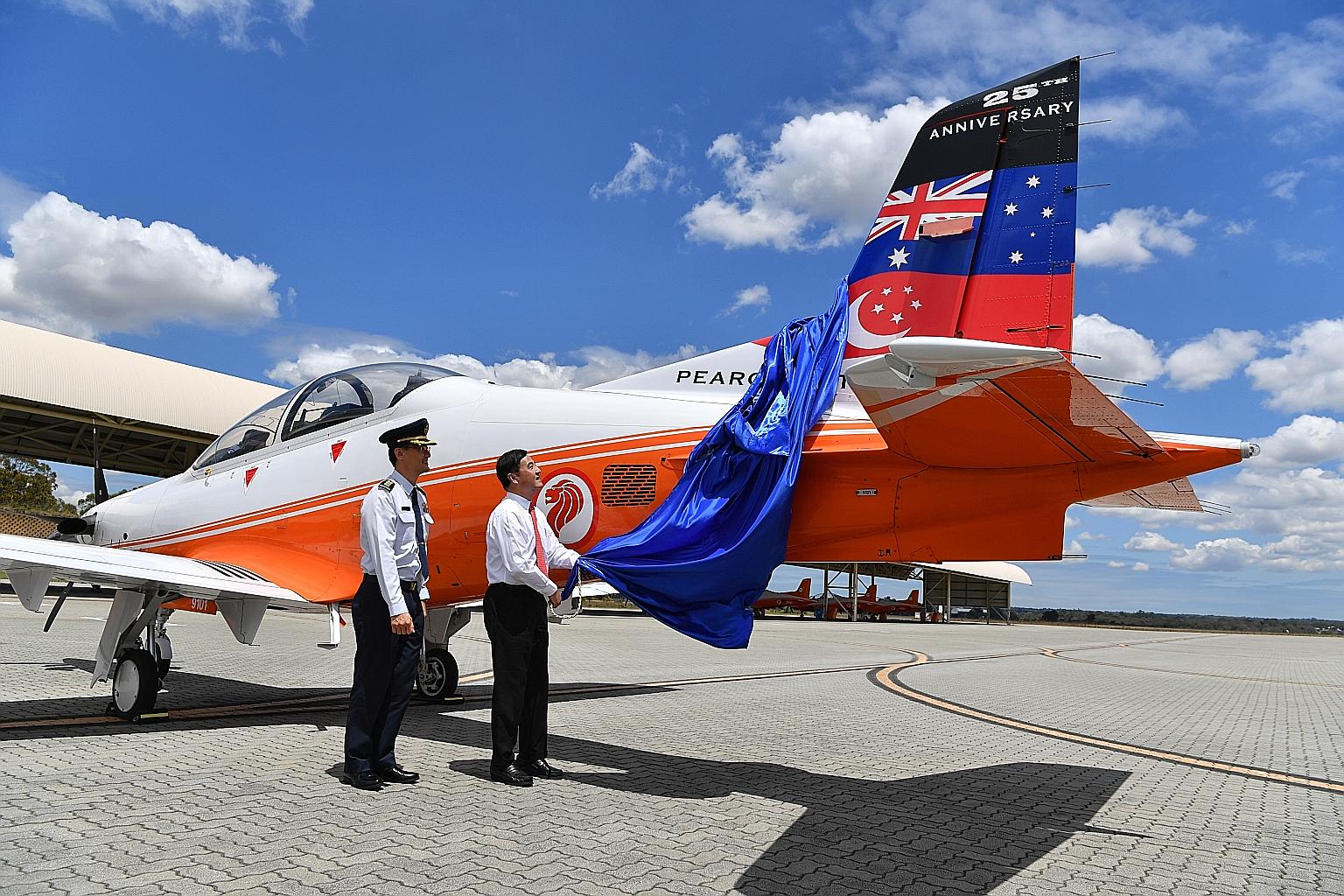 Senior Minister of State for Defence Heng Chee How unveiling the commemorative tail flash on a PC-21 plane at RSAF's 25th anniversary celebration of its training at Base Pearce in Australia yesterday, as commander of the RSAF's Air Force Training Com