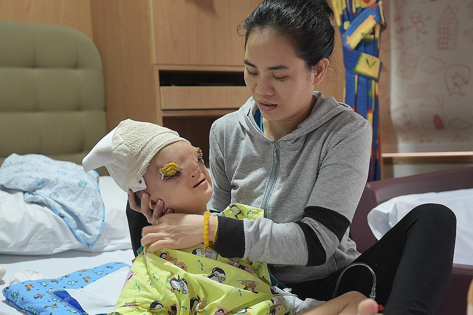 Ton Nu Hoang Dung, seen here after surgery with her mother, Madam Hoang Thi Thuy Linh, was born with a rare deformity where a part of her brain protrudes from a gap in her skull into her face, pushing down her eyes. The medical team took on the case 