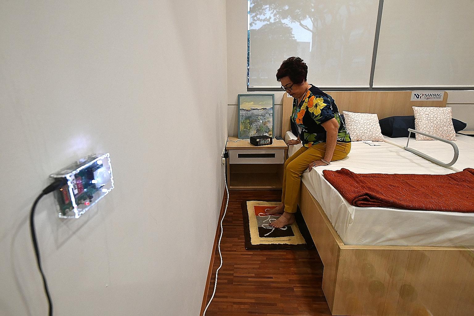 Housewife Lim Siew Kim, 77, demonstrating at Nanyang Polytechnic yesterday how the IoT Night Watcher floormat activates the room light when it is stepped on.