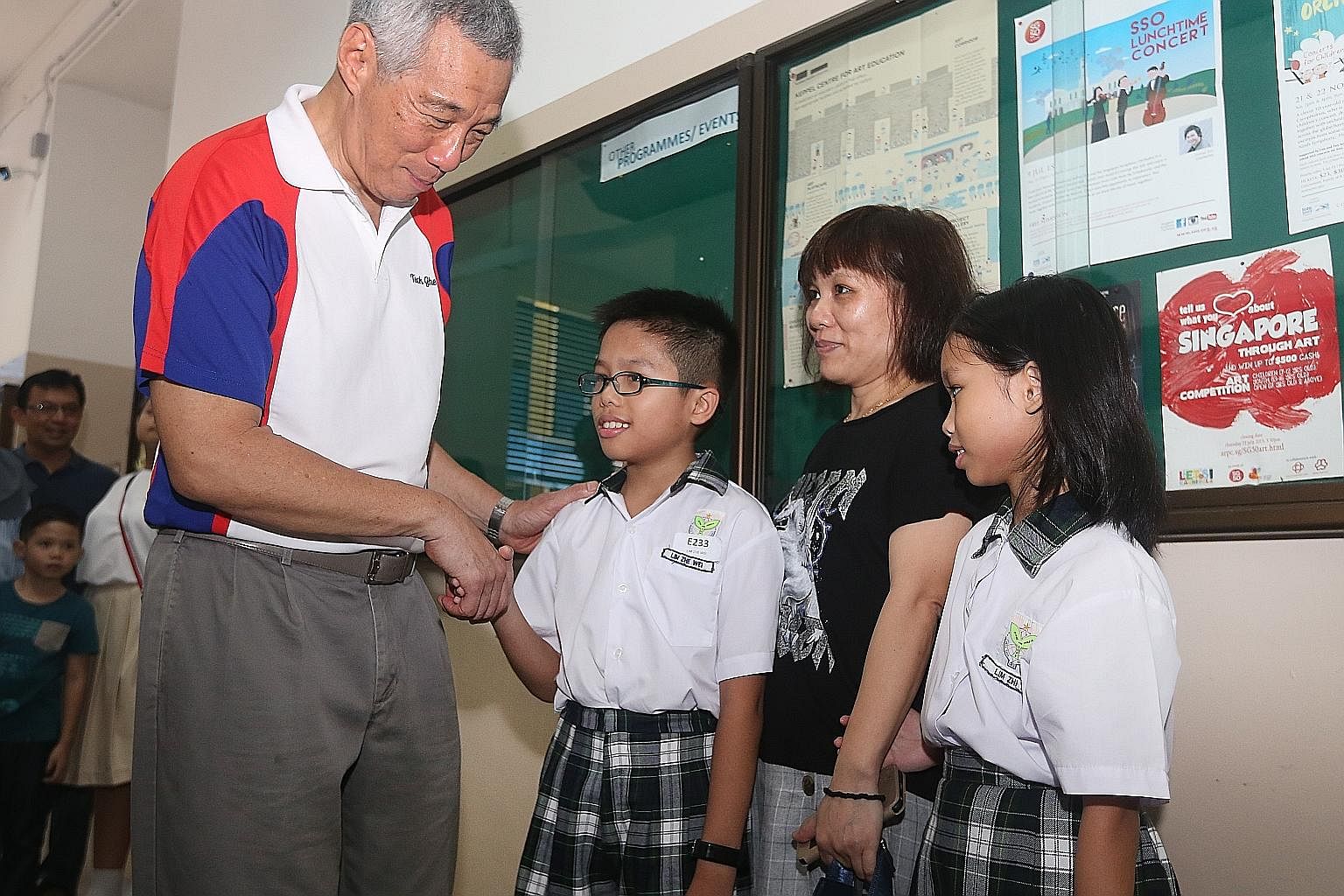 Prime Minister Lee Hsien Loong congratulating Edusave Award recipient Lim Zhe Wei from Teck Ghee Primary School, who is accompanied by his mother Feng Biao Mei and sister Lim Zhi Yi.