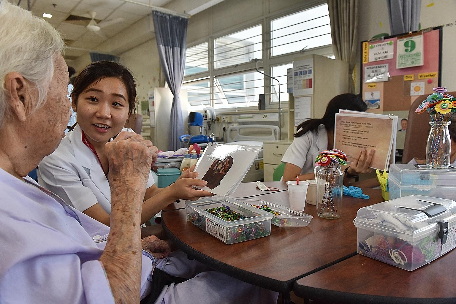 Research assistant Eileen Fabia Goh engaging a patient with flash cards in Tan Tock Seng Hospital's Subacute Geriatric Monitoring Unit. The ward caters to female patients admitted for other medical conditions but also suffer from dementia-related del