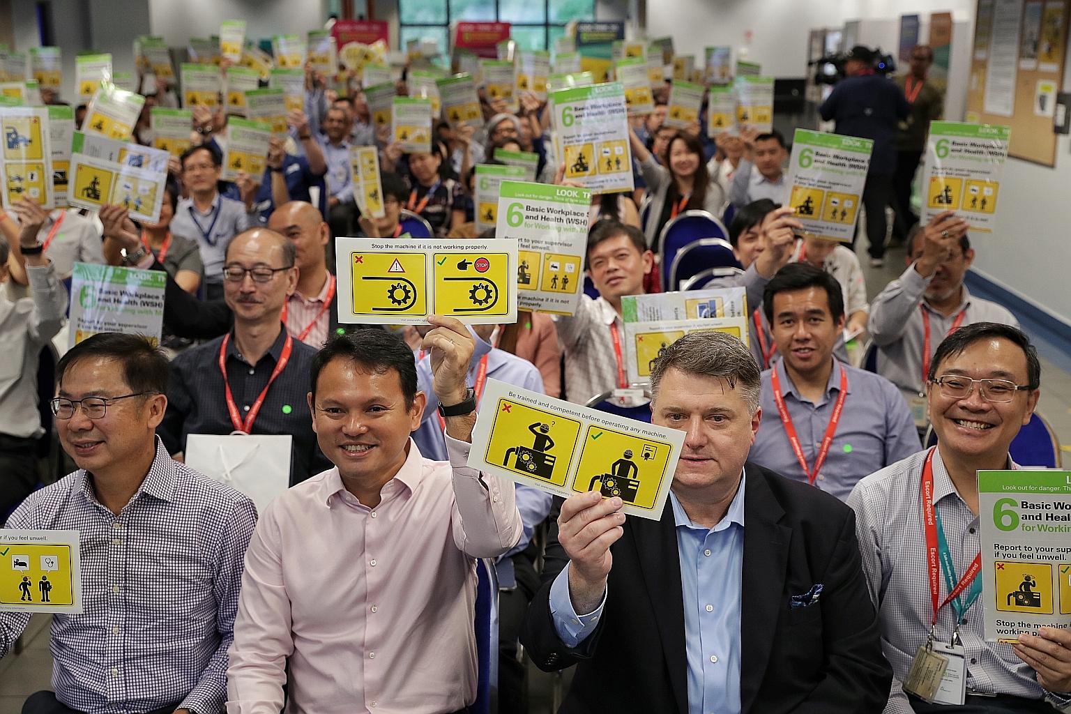 (From left) WSH Council chairman John Ng, Minister of State for Manpower Zaqy Mohamad and SAESL CEO Bill Wozniak holding up workplace safety reminder stickers.
