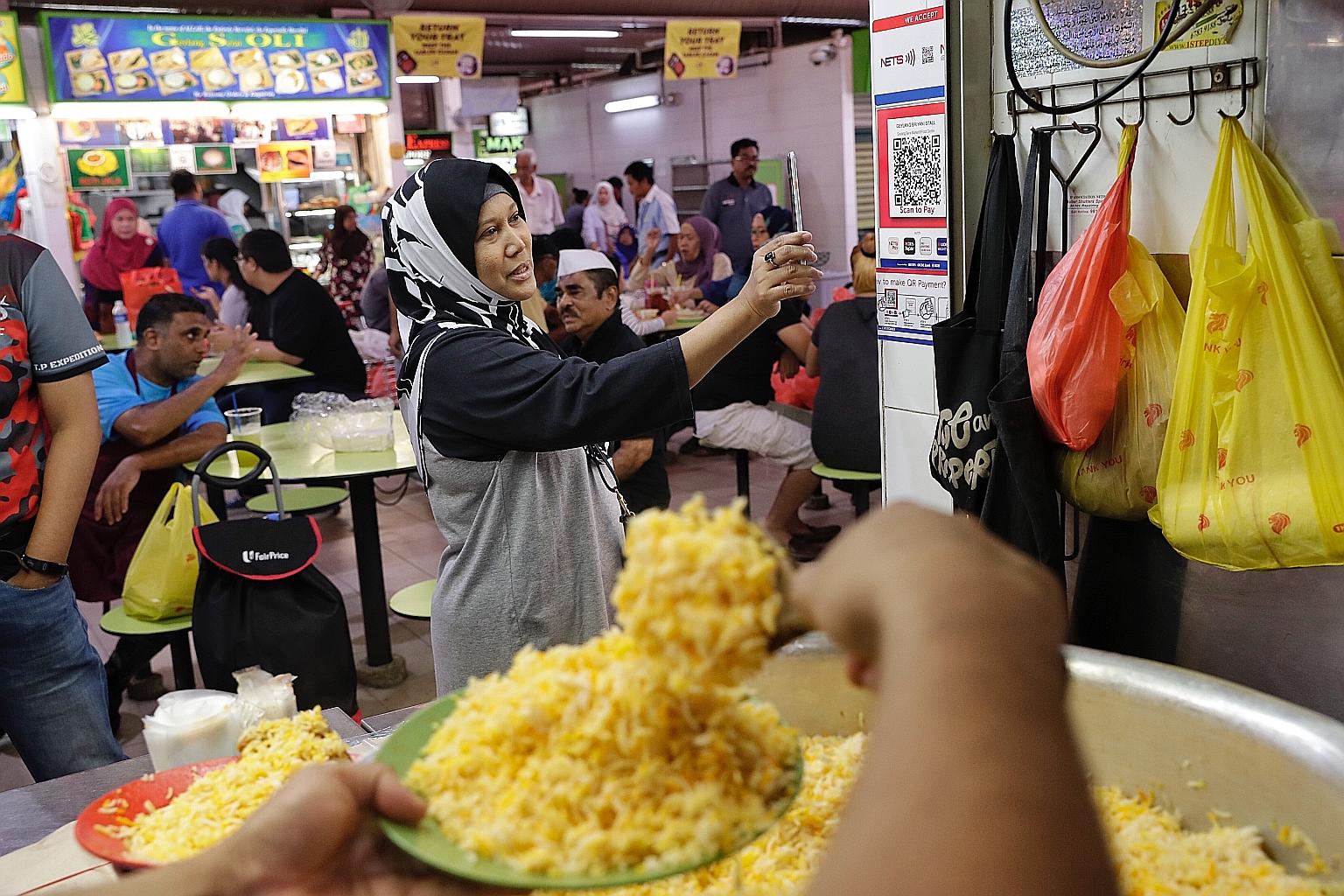 A customer trying out QR code payment at the Geylang Serai Market and Food Centre last September. Under Nets' new initiative, funds from Nets transactions made before 5pm will now be credited to hawkers' bank accounts by 11pm the same day, and procee