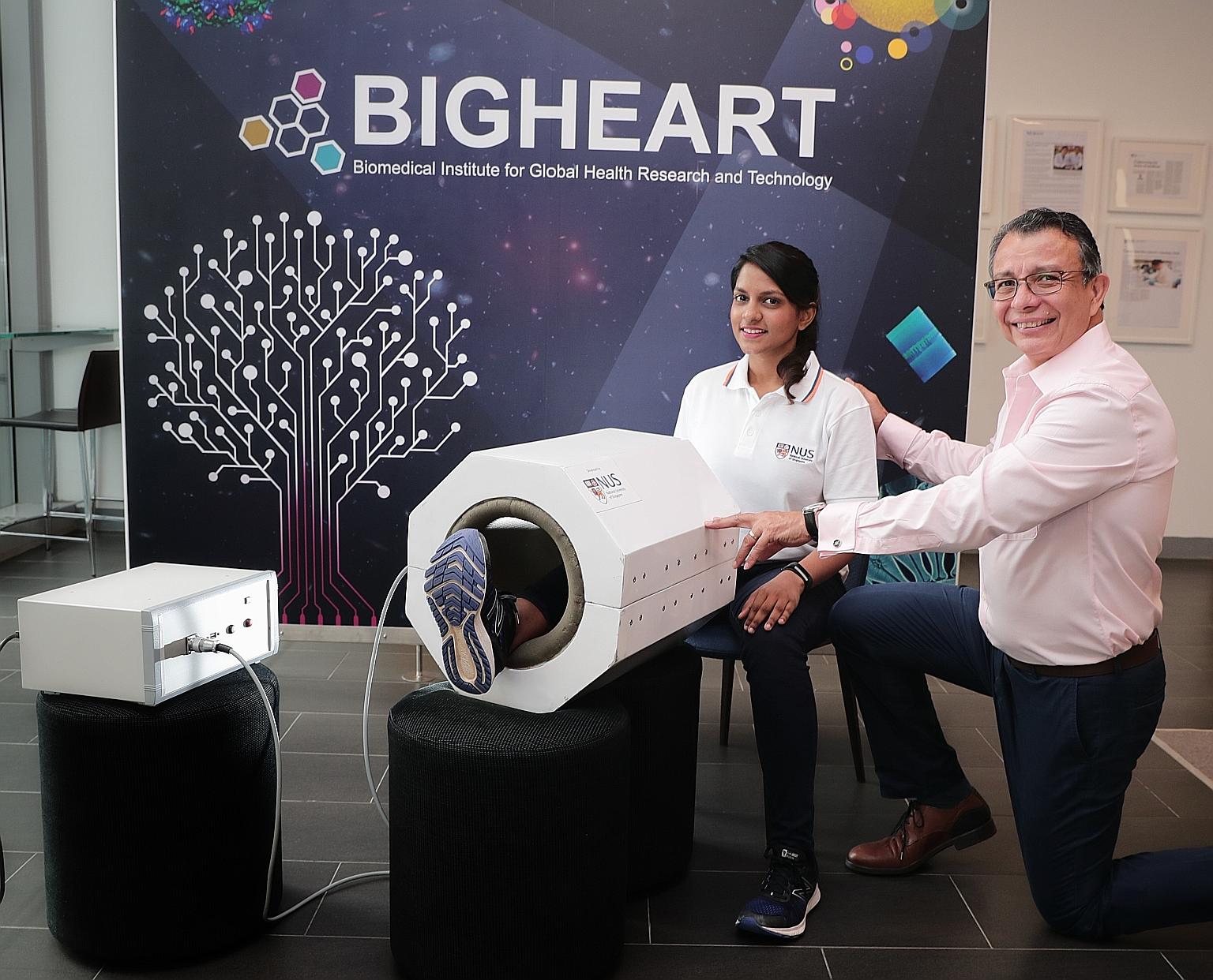 Research assistant Sharanya Ramanan showing how MRegen works, with Associate Professor Alfredo Franco-Obregon. The machine's prototype resembles a miniature MRI scanner that is large enough for a person to insert one leg.