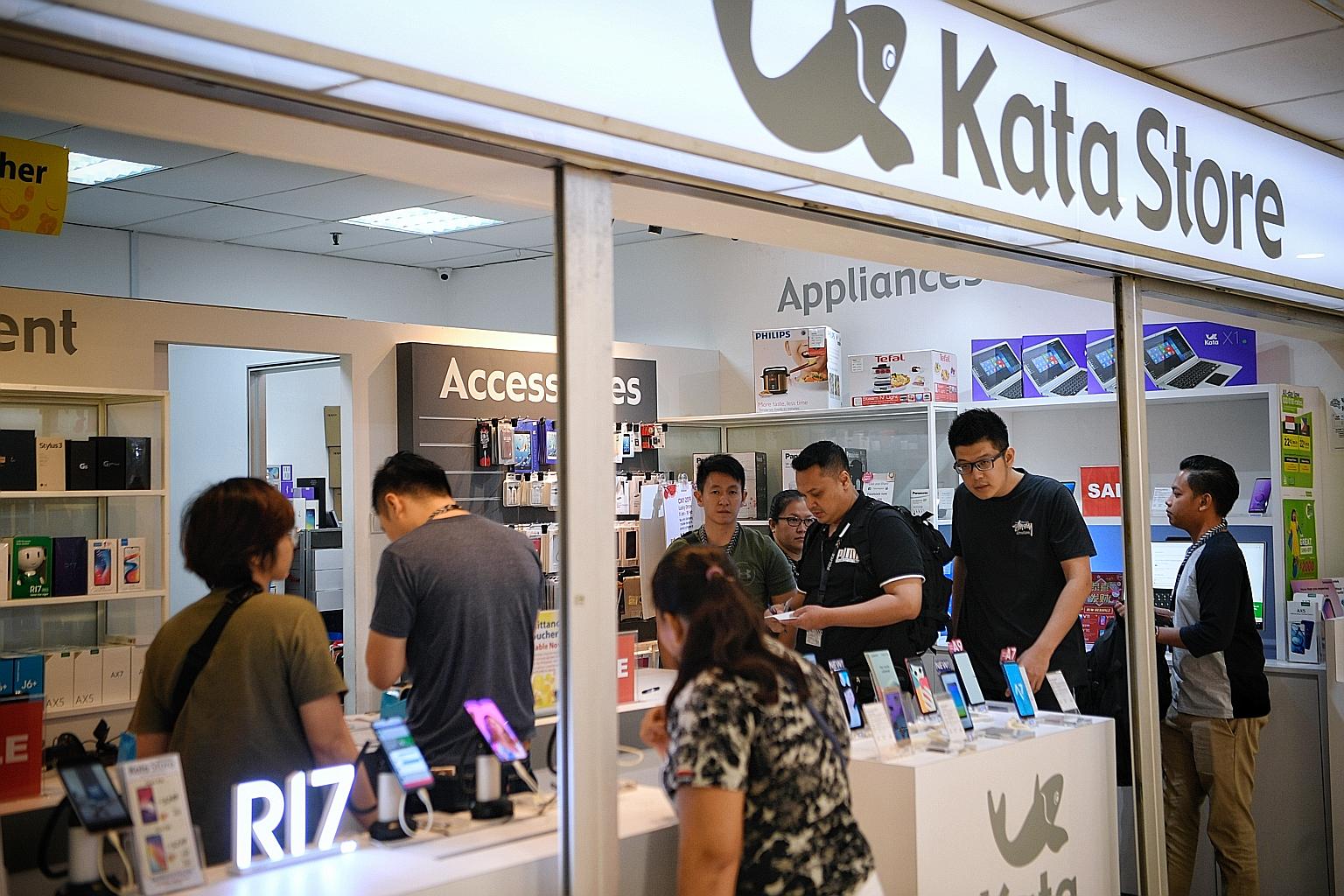 Police officers carrying out a raid on one of cellphone retailer Kata Store's three shops at Lucky Plaza yesterday. Kata, which is not a licensed moneylender, has a tie-up with remittance agency Brunphil Express.