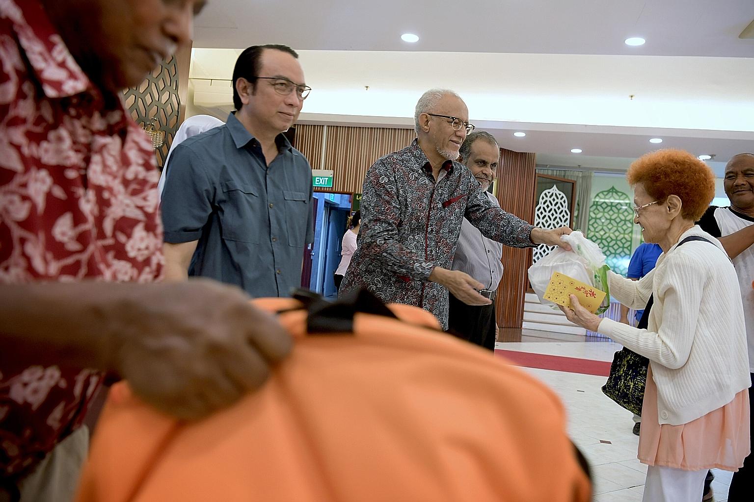 Guest of honour Mohamed Abdullah Alhabshee, President Halimah Yacob's husband, presenting food items to a Jamiyah Singapore beneficiary at the event yesterday. He is flanked by the president of Jamiyah Singapore, Dr Mohd Hasbi Abu Bakar (far left), a