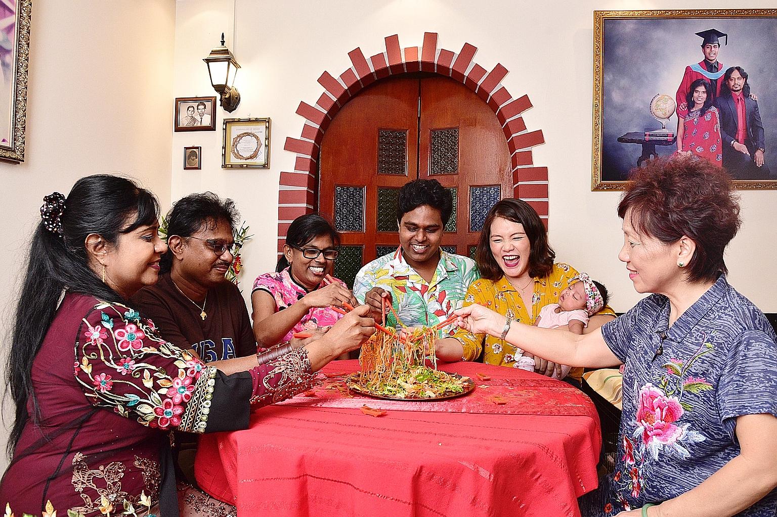 (From left) Ms Stella George, Mr Christopher George, Madam Jenet Nathan, Mr Abraham Christopher, Ms Jacqueline Lui, with eight-week-old Diana Abraham, and Madam Ellen Lim tossing yusheng during their Chinese-Indian reunion dinner.