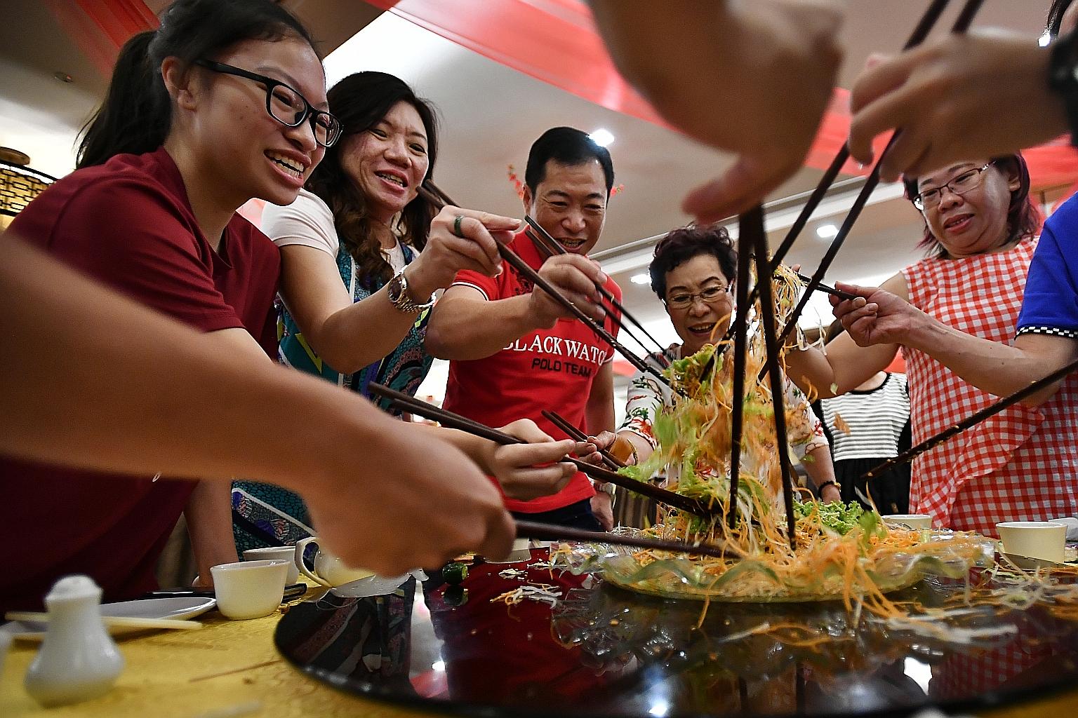 Madam Siah Choo Ing (fourth from left), 79, tossing yusheng with (from left) her granddaughter Krystal Low, 17, daughter-in-law Katharine See, 50, son Kenny Low, 51, and daughter Irene Low, 52, during their reunion lunch at Swatow Seafood restaurant 