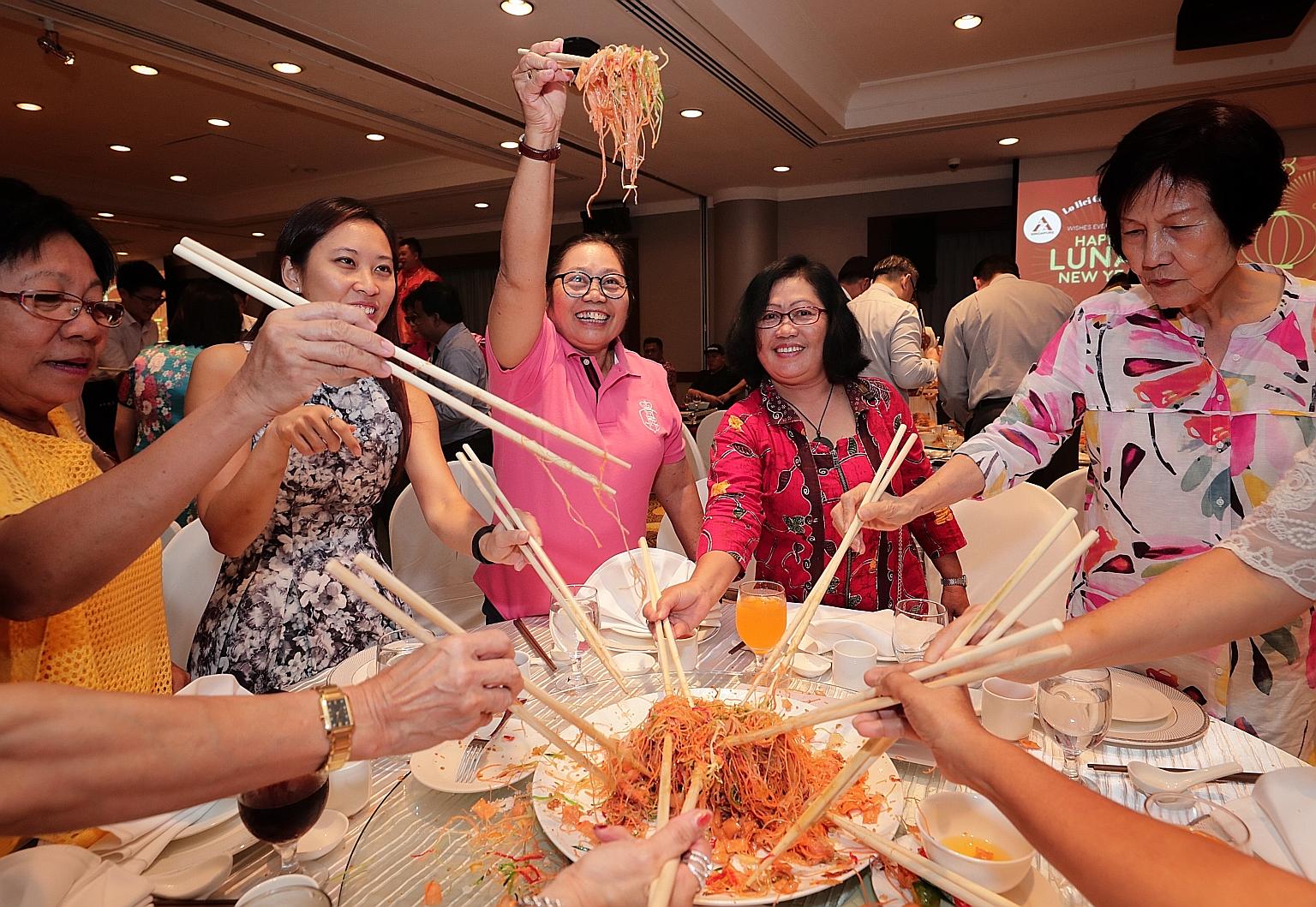 Award recipient Maria Aida Procalla Somejo (in pink), 59, joining in a lo hei session with her employer's daughter, Ms Choo Yuen Ling (second from left), 30, and other guests at the ceremony yesterday. Ms Somejo, who is from the Philippines, has been