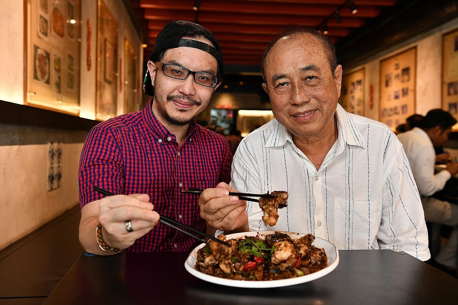 Ka-Soh owner Tang Tat Cheong and his son Cedric with its signature dish of fish head with black bean sauce.