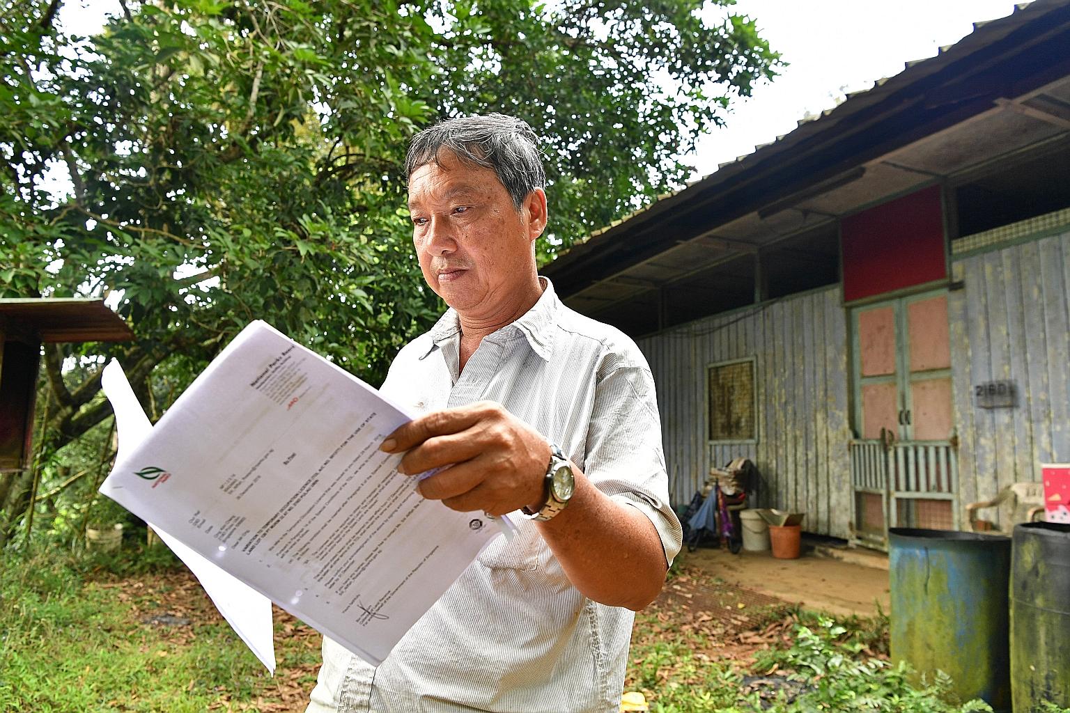 Mr Ong Kim Cheng reading the NParks' Temporary Occupation Licence agreement outside his house. The taxi driver who was born on Pulau Ubin continues to live alone in the house built by his late parents.