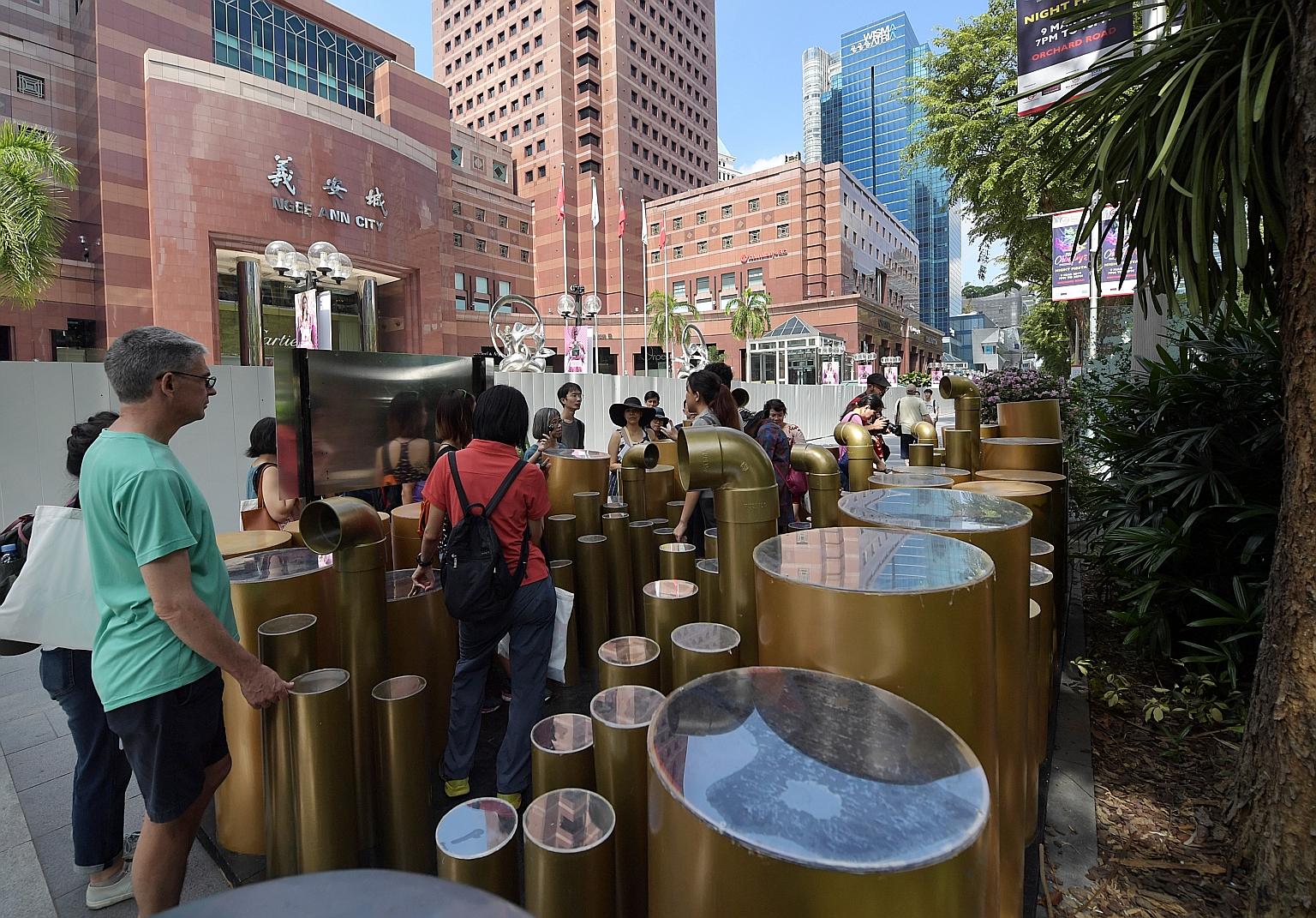 The first of three two-hour walking tours in the Orchard Road area was held yesterday. Here, the group is viewing an art installation outside Ngee Ann City mall titled Orchard: A Stroll Between Valleys.