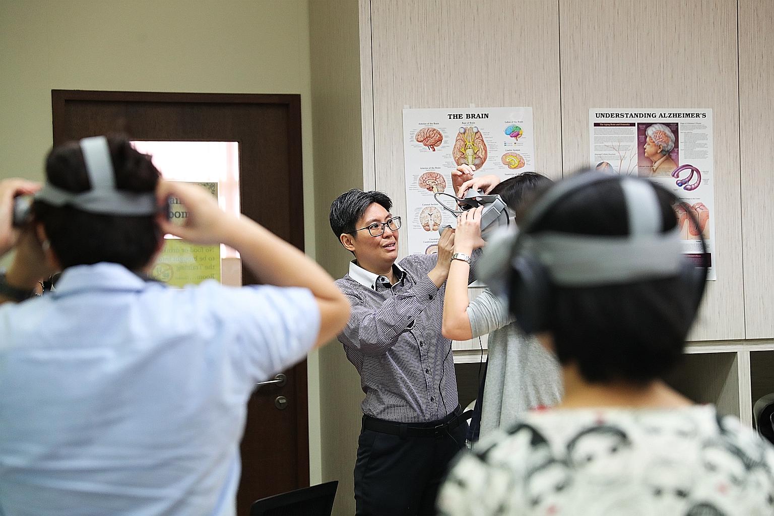 Ms Joanne Loy, a programme coordinator at the Alzheimer's Disease Association, helping a participant with a virtual reality headset at a workshop yesterday.