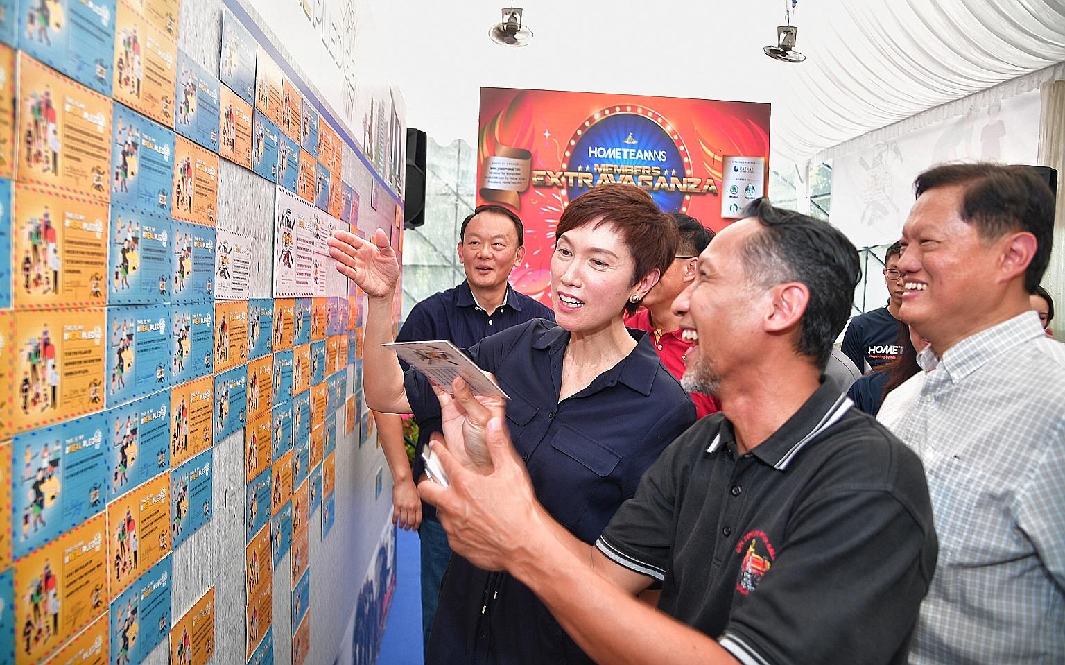 HomeTeamNS president Josephine Teo with two men who served in the Home Team previously, Mr Edwan Nizar Ahadan (foreground), 46, and Mr William Tan (in white), 62, looking at the pledges made by NSmen to reaffirm their commitment to serve and protect