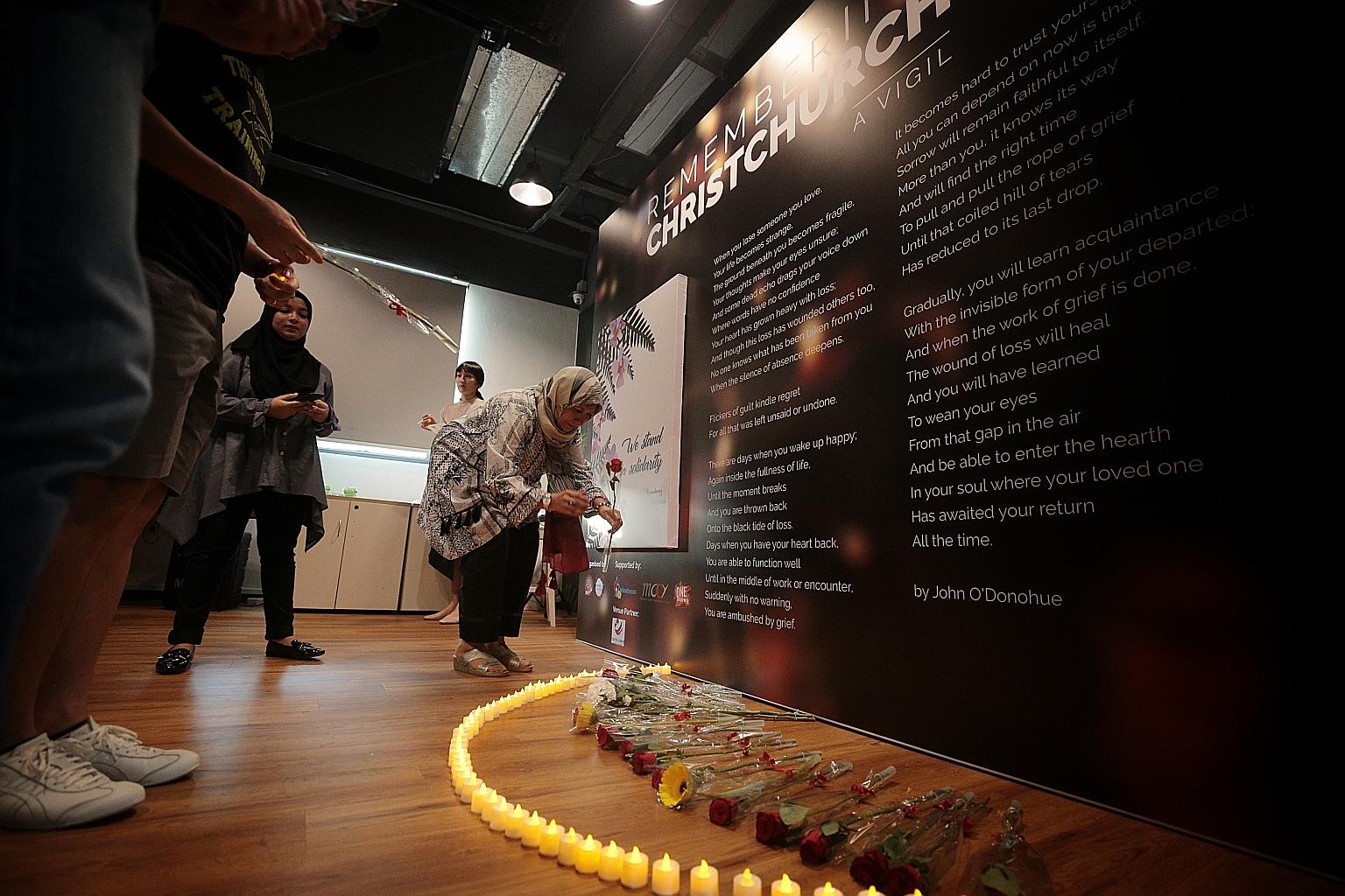 Ms Nafisa Kapadia, 61, placing a flower during a vigil at The Red Box in Somerset Road yesterday in memory of the Christchurch attack victims.