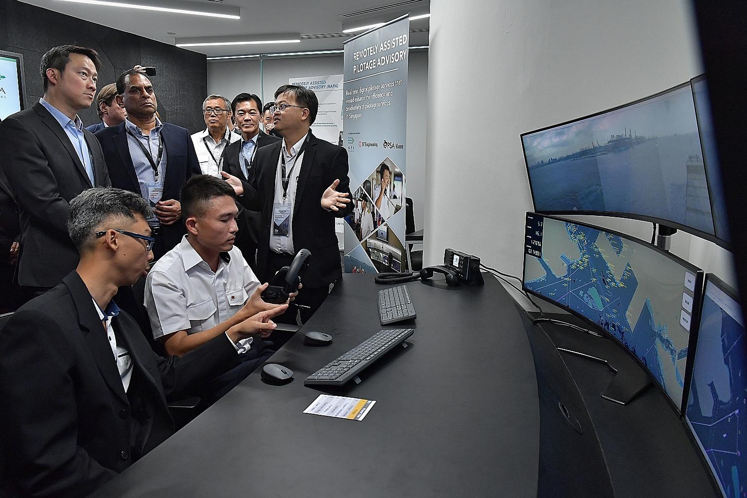 Senior Minister of State for Transport Lam Pin Min (left, standing) being briefed in the Maritime and Port Authority of Singapore's Maritime Innovation Lab yesterday on a remote piloting system that is being developed to allow vessels to be remotely 