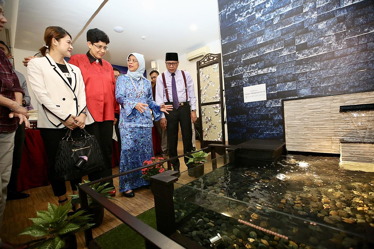 President Halimah Yacob, flanked by Ain Society chief executive Mohamad Yusof Ismail and the society's medical adviser, Marine Parade GRC MP Fatimah Lateef, admiring a water feature in the society's new cancer centre yesterday at Block 9 Haig Road. A