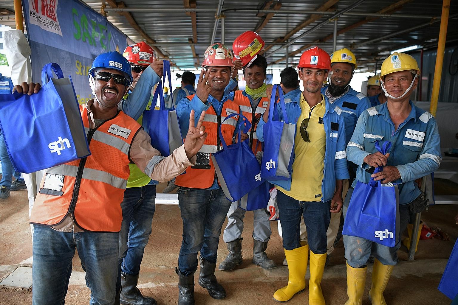 Workers with their Singapore Press Holdings (SPH) goodie bags yesterday. The labourers work on The Woodleigh Residences, an integrated development by Kajima Development and SPH. The gifts were given to mark Labour Day today. ST PHOTO: KUA CHEE SIONG