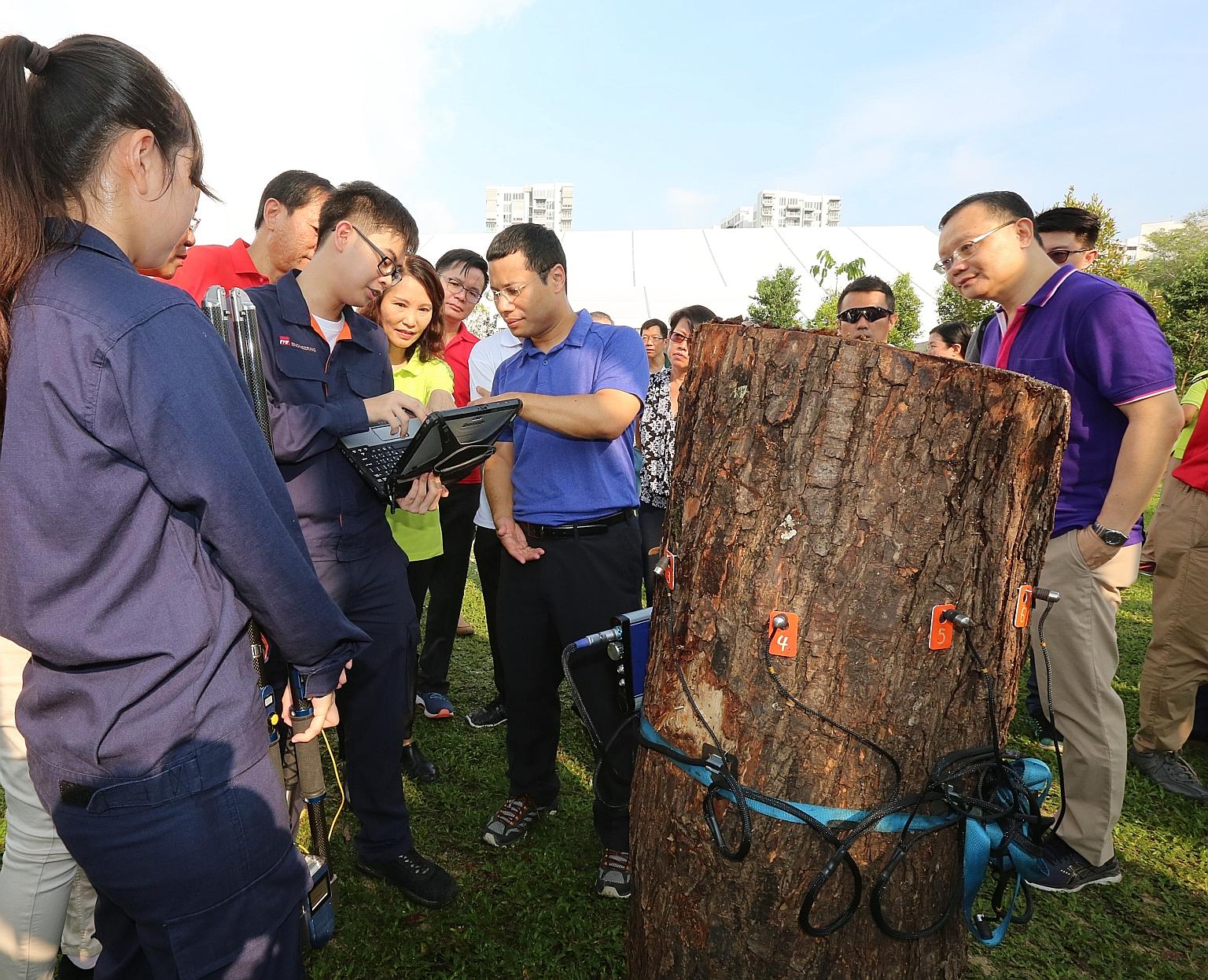 Second Minister for National Development Desmond Lee (centre) being briefed by students on how they use equipment to assess the condition of trees. He said that adopting more advanced technology will not only improve productivity but also attract a n