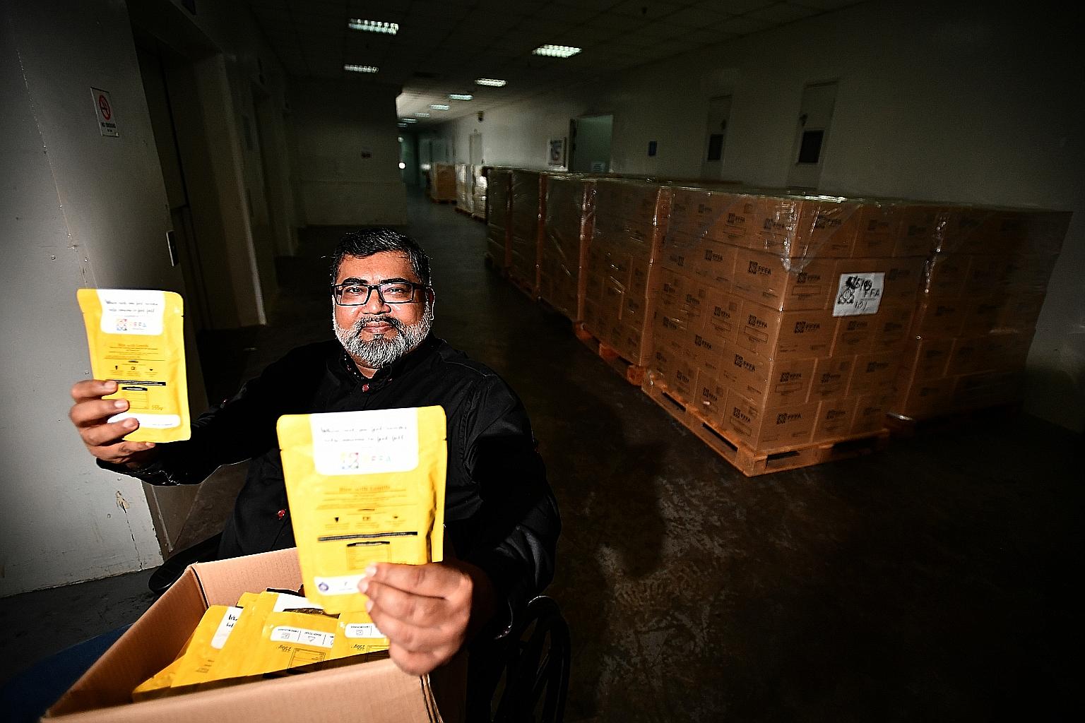 Free Food For All founder Nizar Mohamed Shariff showing some of the ready-to-eat local meals in retort pouches. Behind him are cartons containing the food packages. The charity will be delivering 800 of such cartons to 800 needy households during Ram