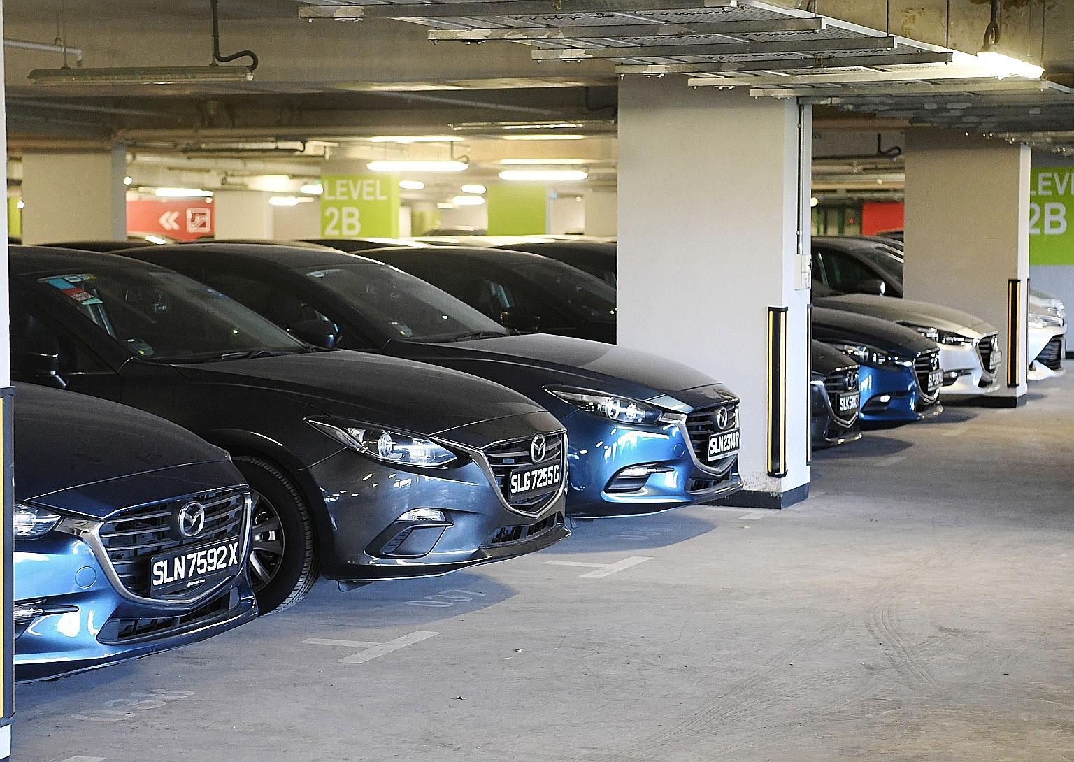 Unused private-hire cars at the Singapore Sports Hub last month. Industry estimates put the fleet of unused vehicles - mostly left behind by Uber - at over 2,000. Yet, to entice drivers, the private-hire sector has placed orders for hundreds of BMW,