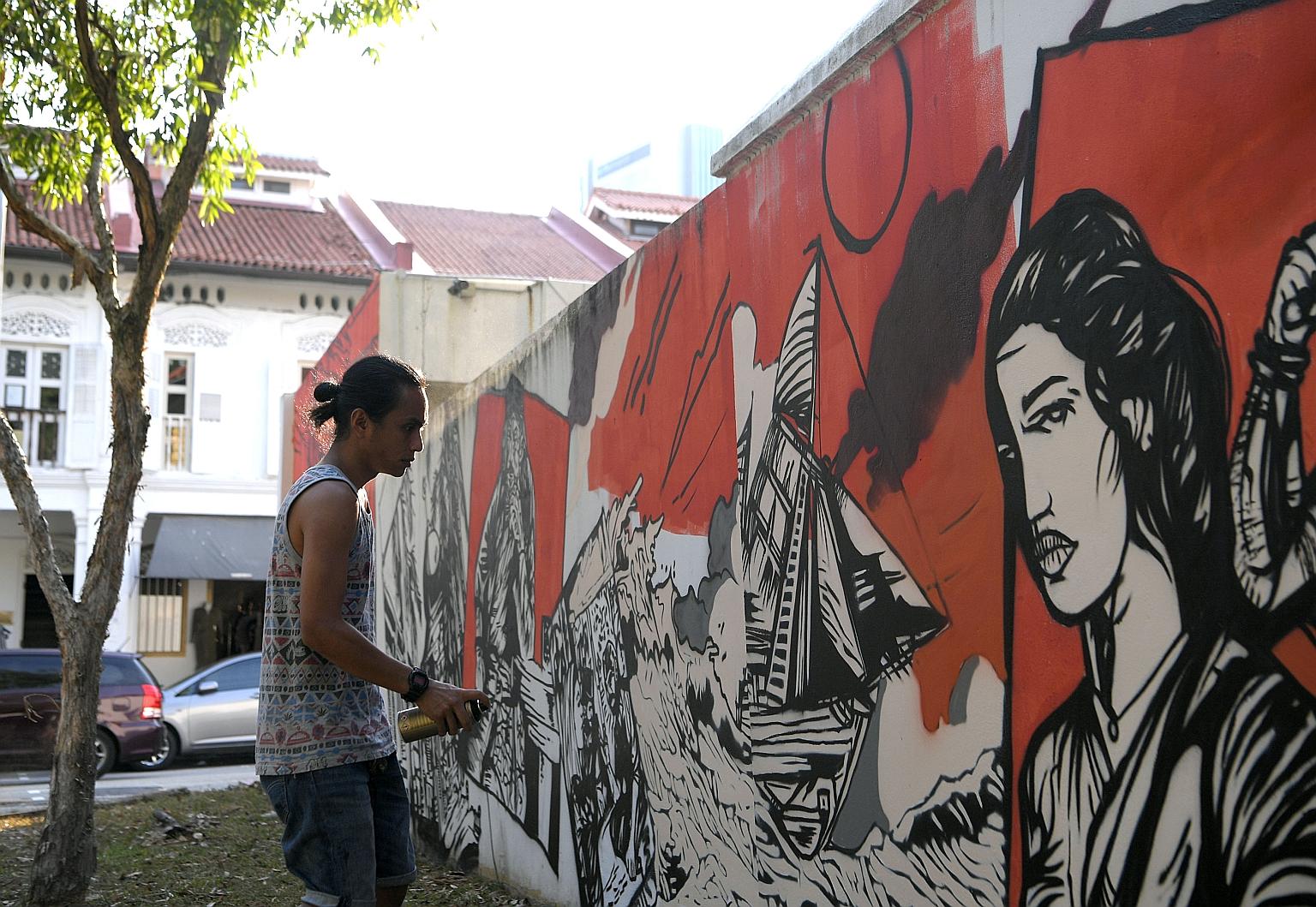 Artist Zul Othman shown here painting the wall surrounding Gedung Kuning, a historical royal building in Kampong Glam. Mr Zul's mural tells the tale of Wak Cantuk, who went on a killing spree in the 1800s after his marriage proposal was rejected. Som