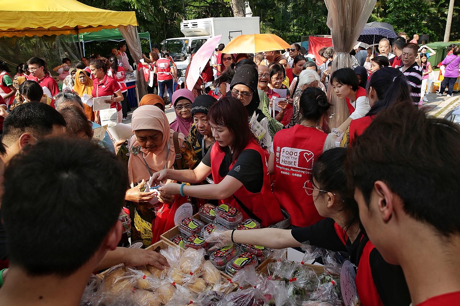 Residents queueing up for fresh produce at a Food From The Heart booth during yesterday's carnival to celebrate Marine Parade Town Council's 30th anniversary. 