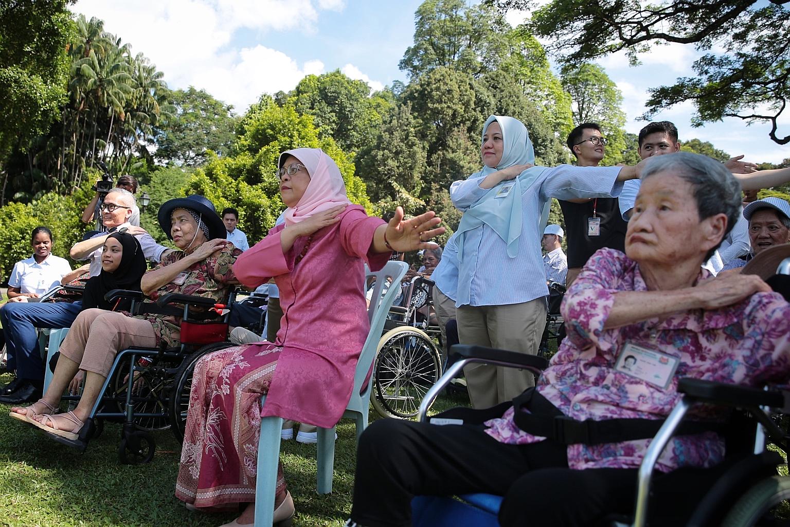 President Halimah Yacob doing wheelchair yoga with residents of the Thong Teck Home for Senior Citizens at the Istana yesterday.