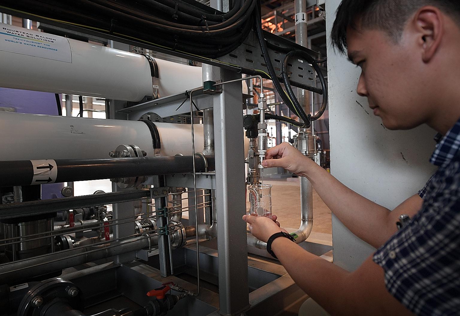 Mr Chua Cheng Teck demonstrates the clarity of treated water at Wyeth Nutritionals (Singapore), a company which worked with PUB to instal water-recycling facilities in its operations. ST PHOTO: ALPHONSUS CHERN