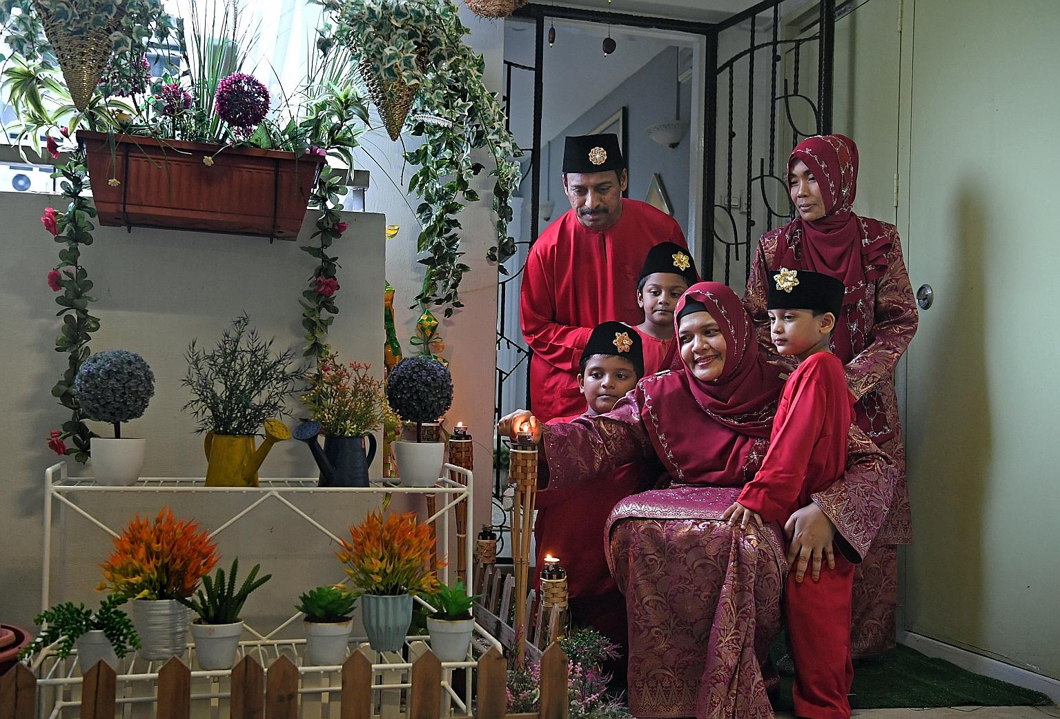 Ms Norkhatilah Maricar with her husband Safza, 43, their children Sohayl, four, Suhaym, six, and Sayf, nine, and maid Leni (standing), 37. They have set up lampu pelita, traditional lamps used during the festivities, outside their flat in Eunos. ST P