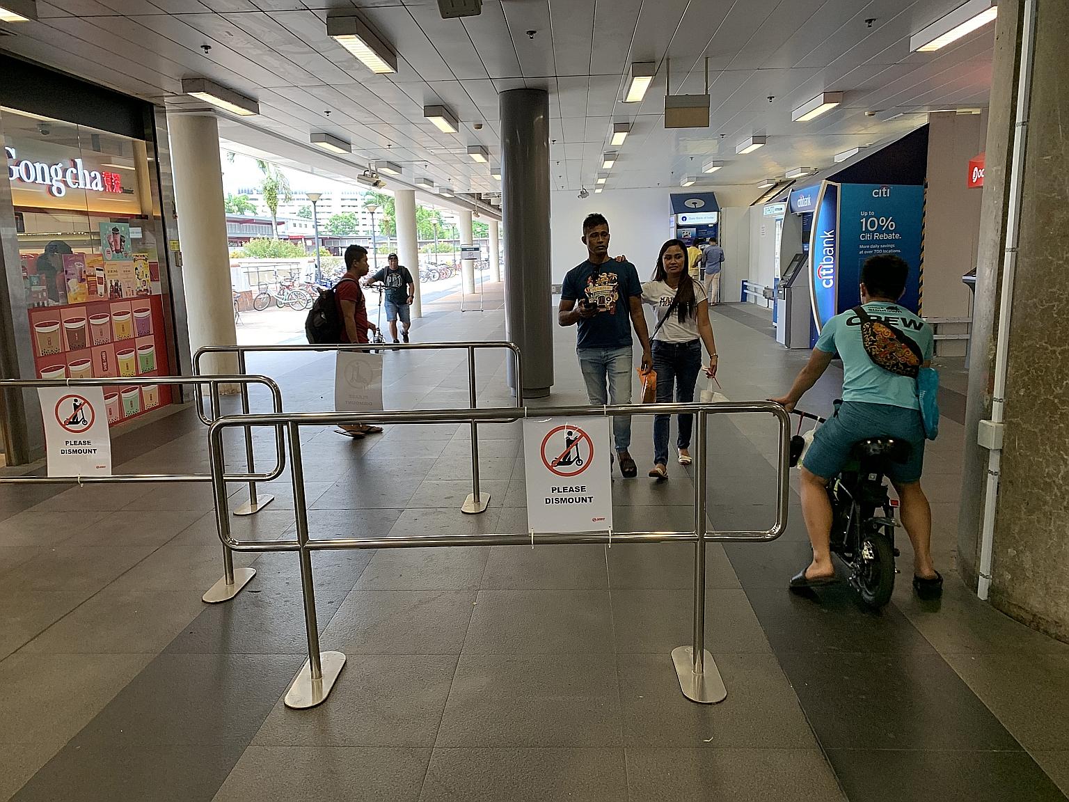 A man riding his personal mobility device through a gap in the metal barriers, which were set up to get riders to dismount inside the Woodlands MRT station compound. SMRT is trialling the use of such barriers to improve safety for commuters. ST PHOTO