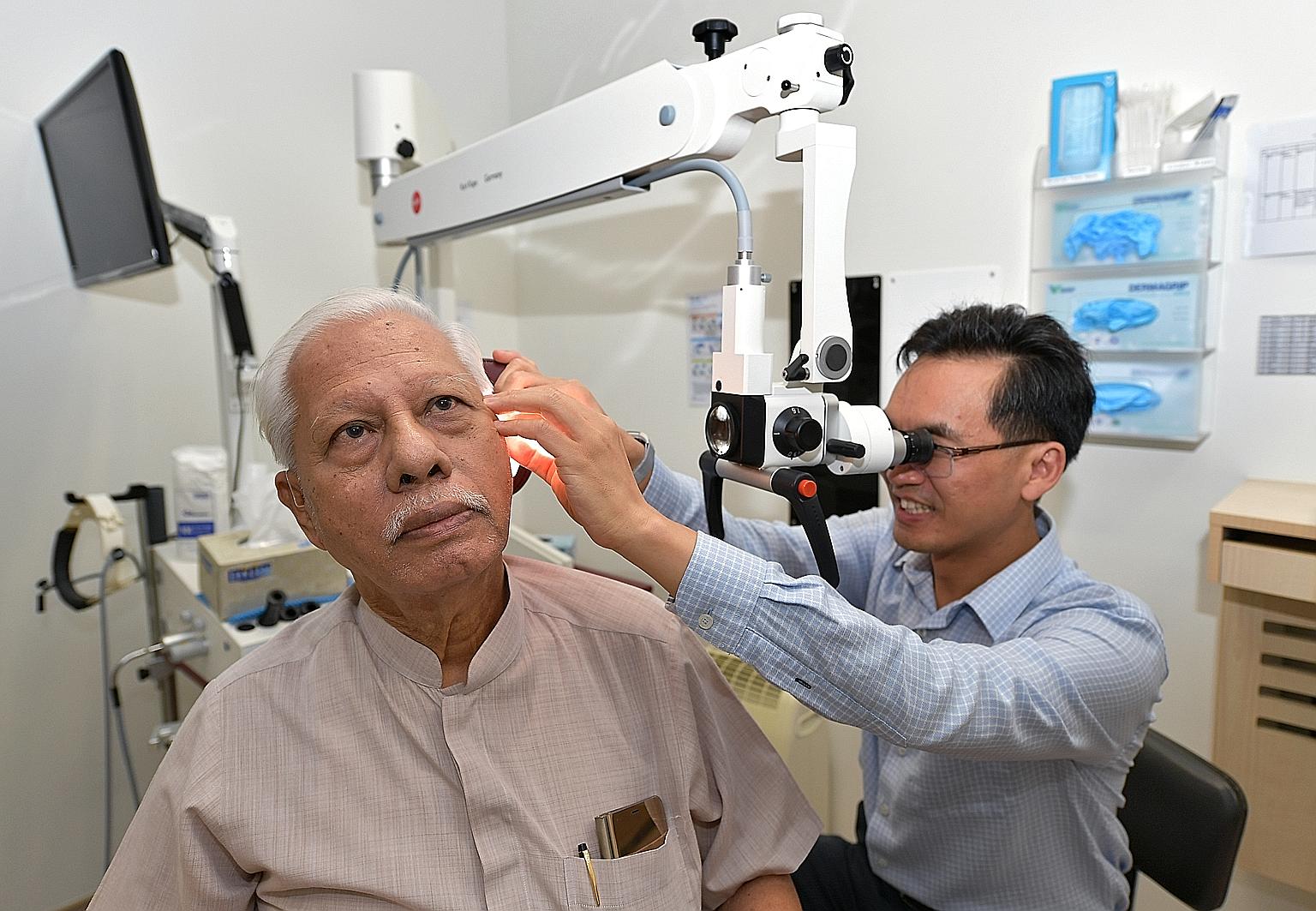Tan Tock Seng Hospital's senior ear, nose and throat consultant Ho Eu Chin doing an ear check-up on his patient, Mr Doraisamy Pillay.