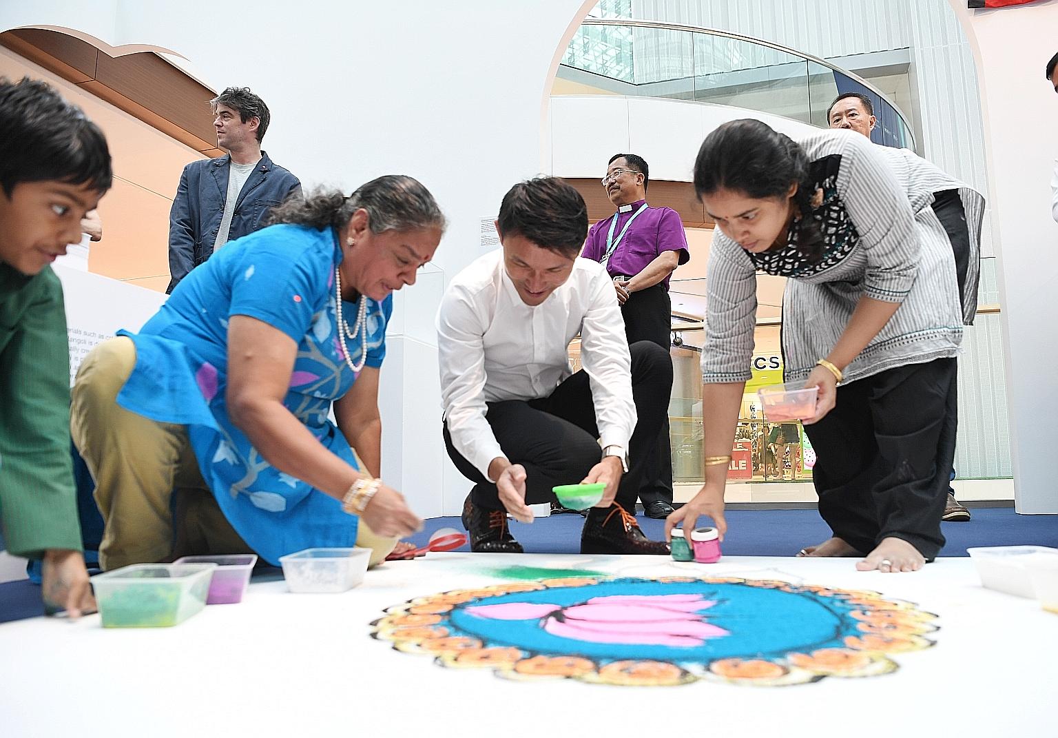 Senior Parliamentary Secretary for Culture, Community and Youth Baey Yam Keng joining Madam Vijaya Mohan, her grandson Pravan Bakshi and niece Amirta Ravikumaran in giving the finishing touches to rangoli art at the launch of the Many Beliefs, One Fu